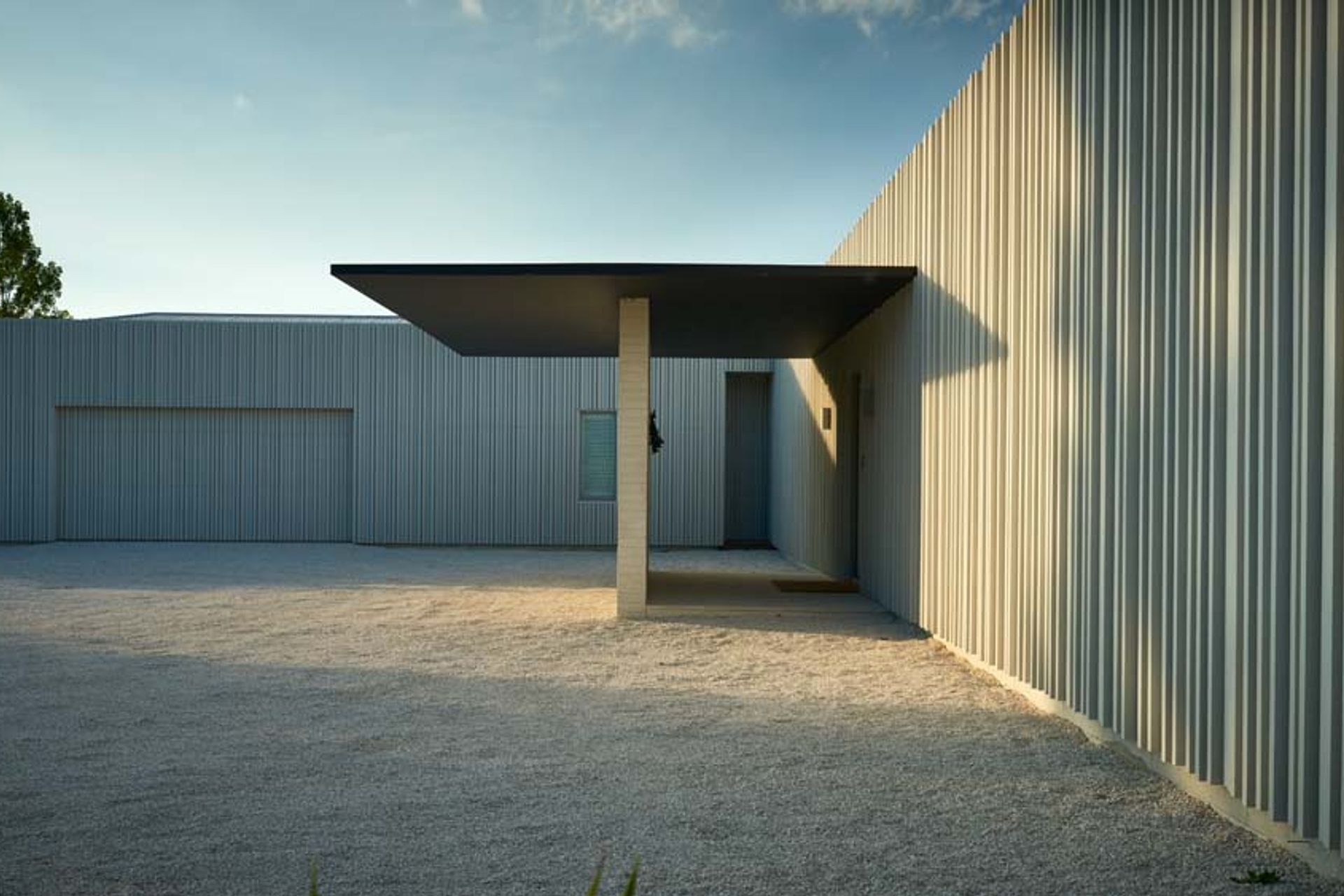 The garage (left) recedes into the white-painted cedar cladding, which is decorated with non-repeating vertical battens.