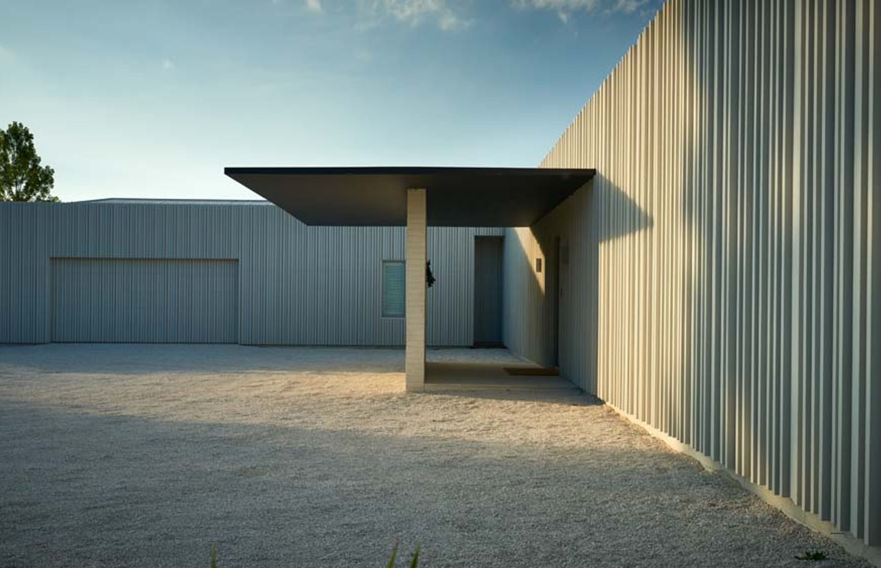 The garage (left) recedes into the white-painted cedar cladding, which is decorated with non-repeating vertical battens.