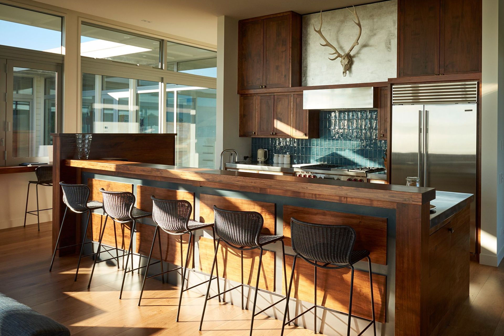The practical chef's kitchen is a celebration of timber, with handmade sea-blue tiles, a chef's hob, and a carrera marble benchtop for making pastries. In behind is a wet and dry pantry.