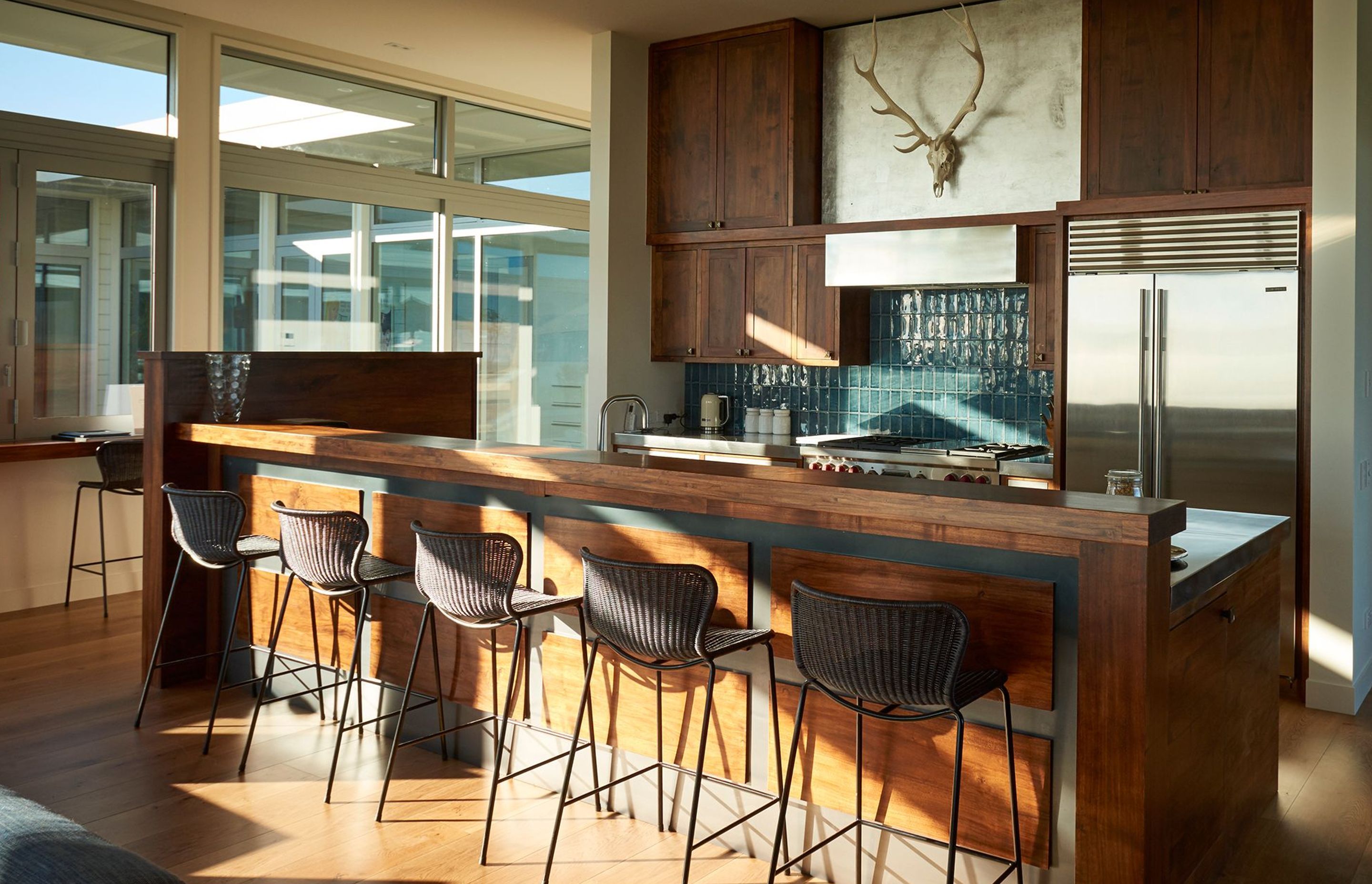 The practical chef's kitchen is a celebration of timber, with handmade sea-blue tiles, a chef's hob, and a carrera marble benchtop for making pastries. In behind is a wet and dry pantry.