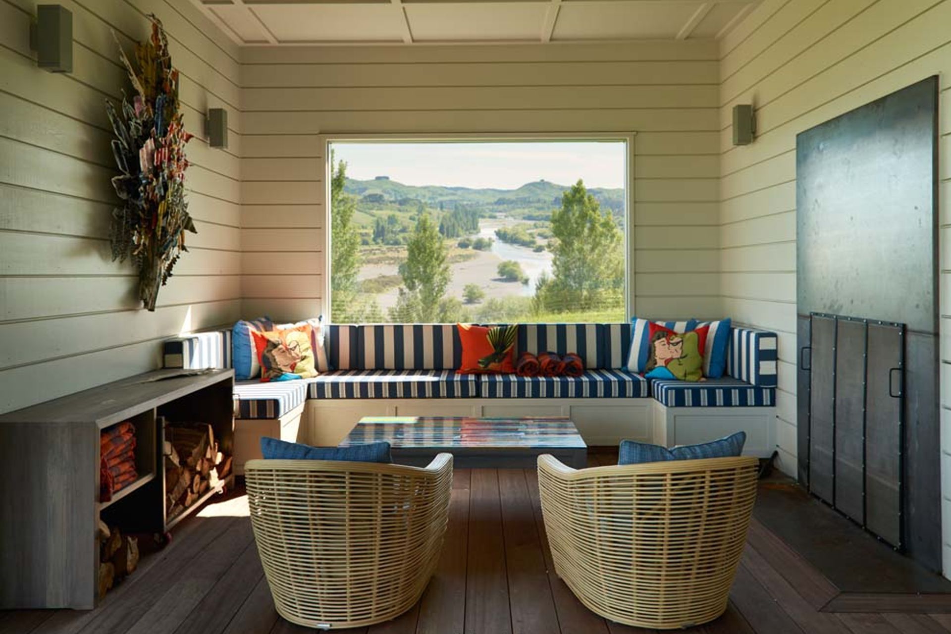 The lounge area in the outdoor room has built-in bench seating, a metal-panelled fireplace and a perfectly framed view of the Tukituki River.