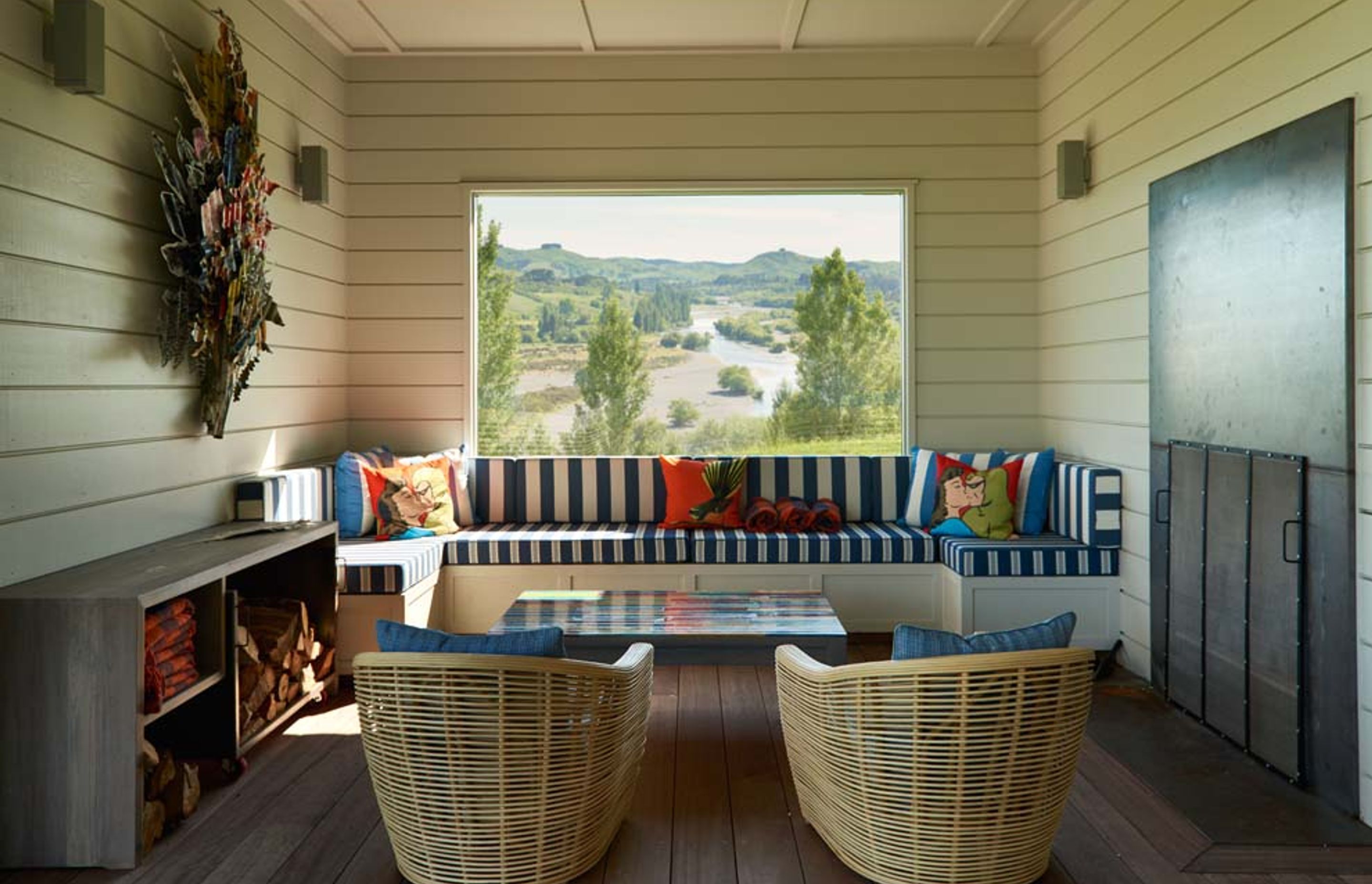 The lounge area in the outdoor room has built-in bench seating, a metal-panelled fireplace and a perfectly framed view of the Tukituki River.