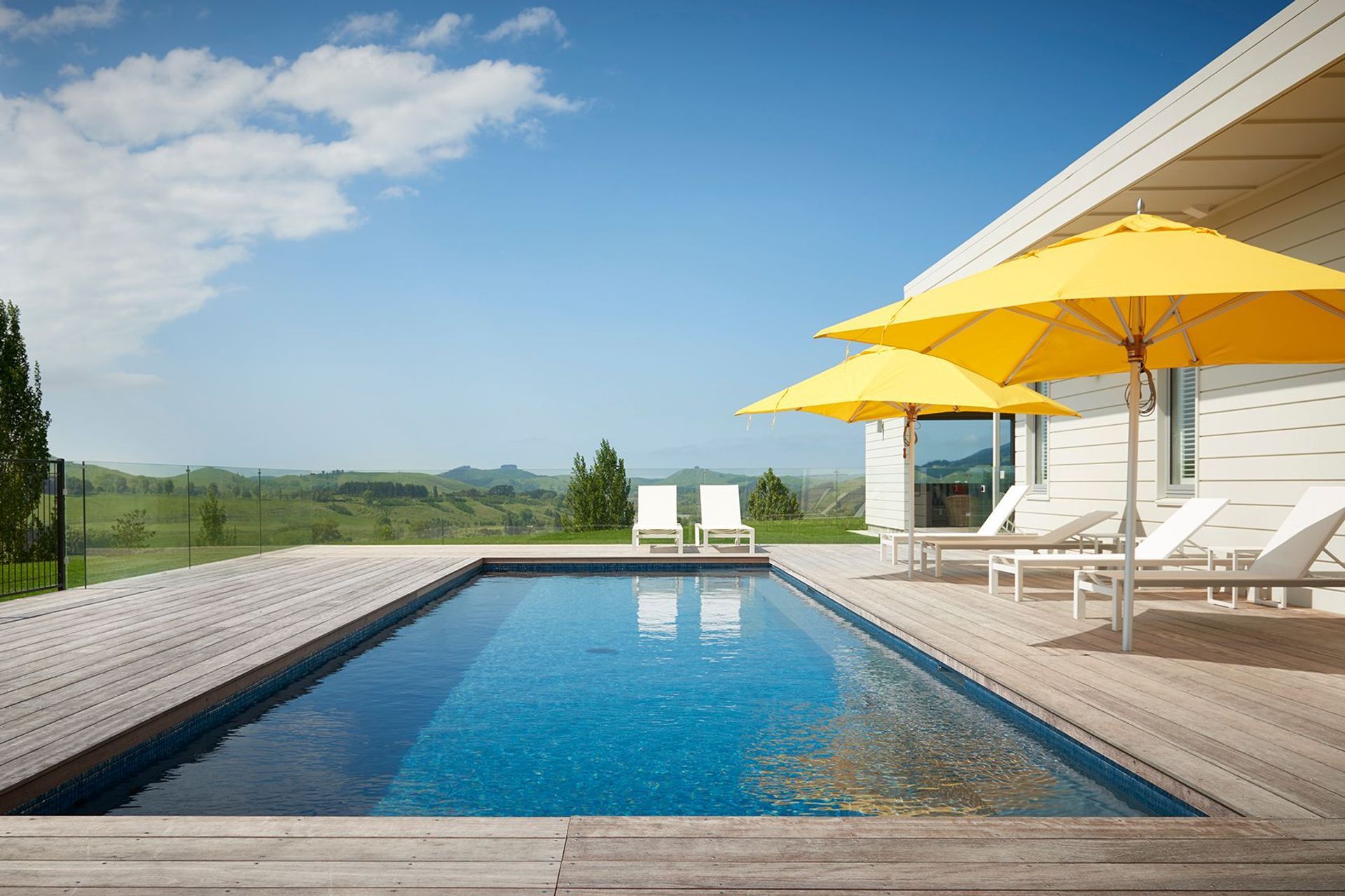 The pool area is surrounded by glass balustrades to enhance the views of the landscape.