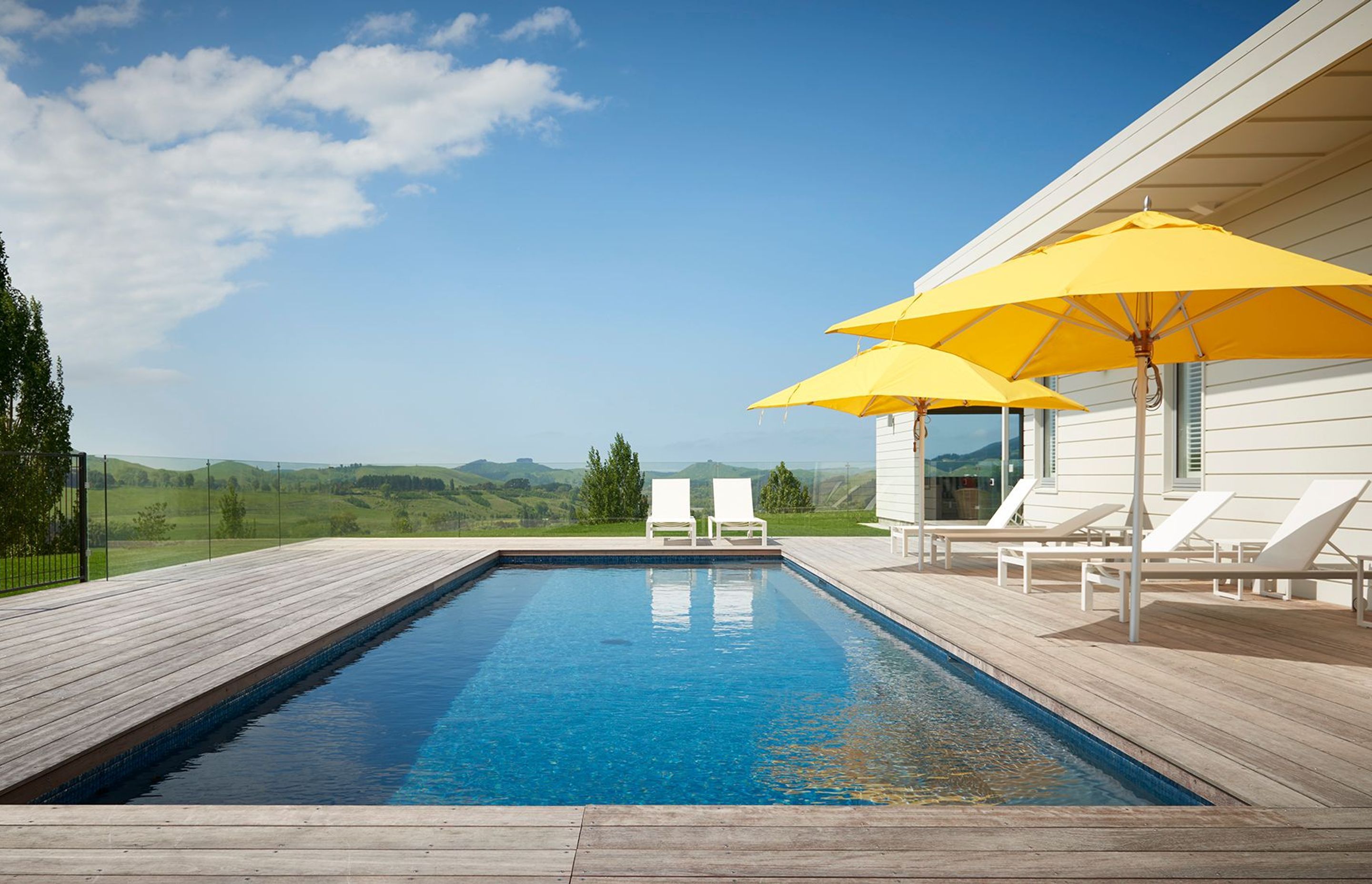 The pool area is surrounded by glass balustrades to enhance the views of the landscape.