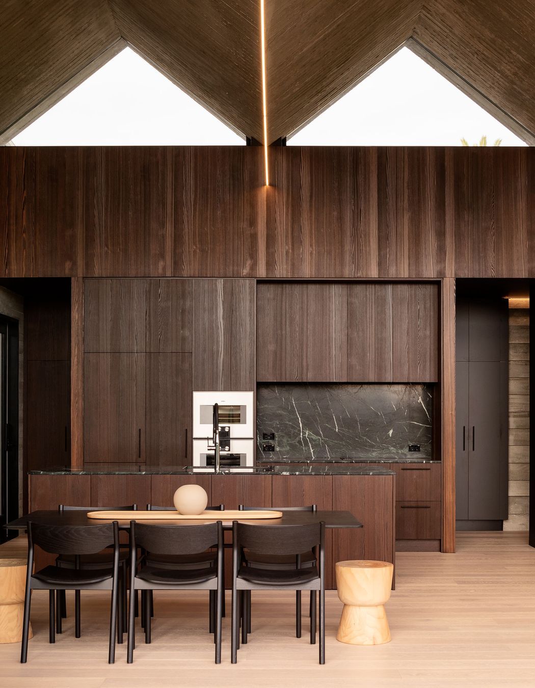Dark timber panelled cabinetry provides a nice contrast to the blonde timber flooring.