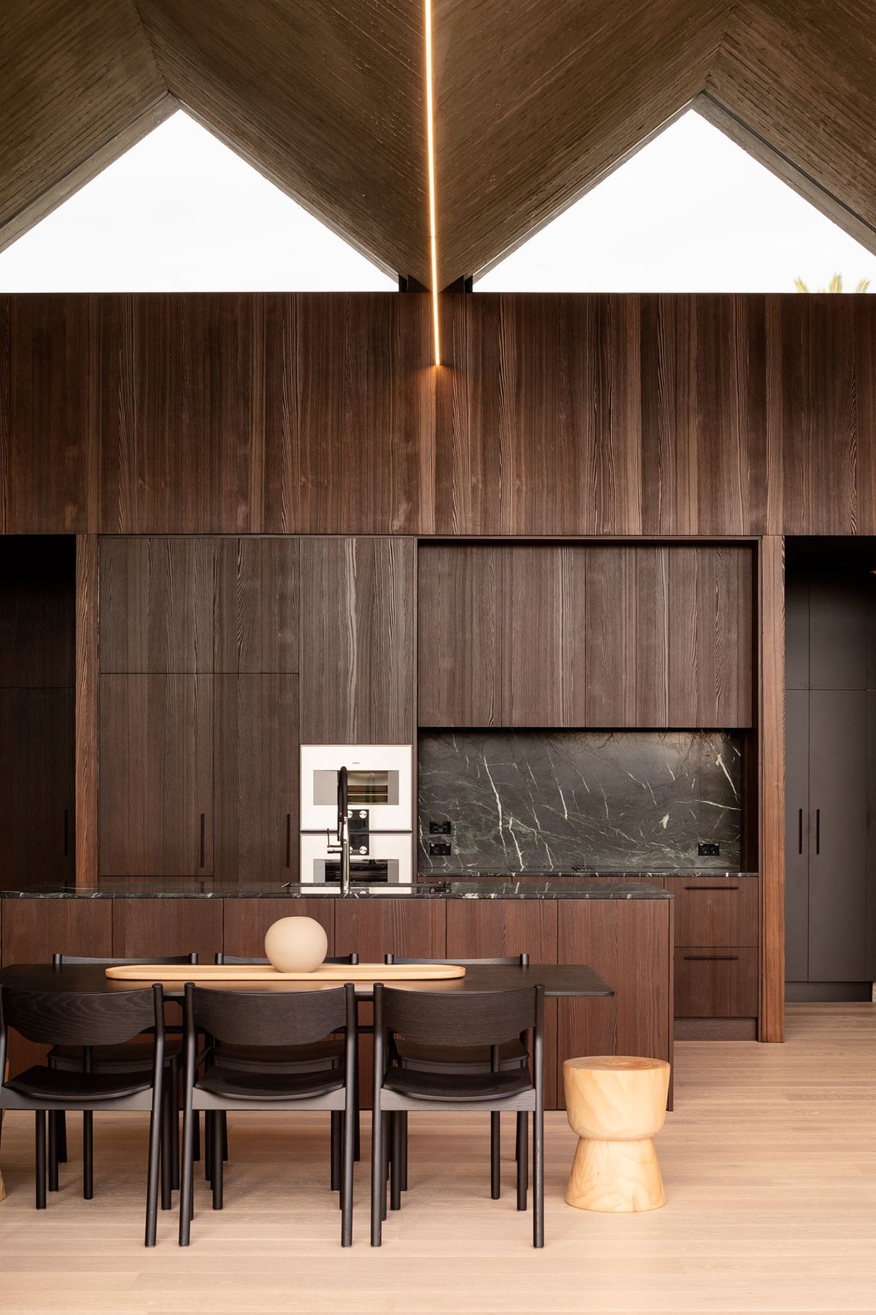 Dark timber panelled cabinetry provides a nice contrast to the blonde timber flooring.