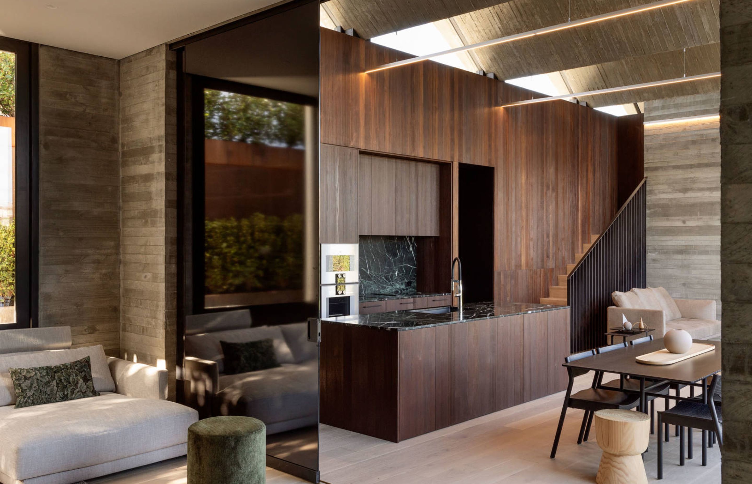 Glass sliding doors open and close up a lounge area off the kitchen and dining area. Triangular glazed clerestory windows draws light into the kitchen.