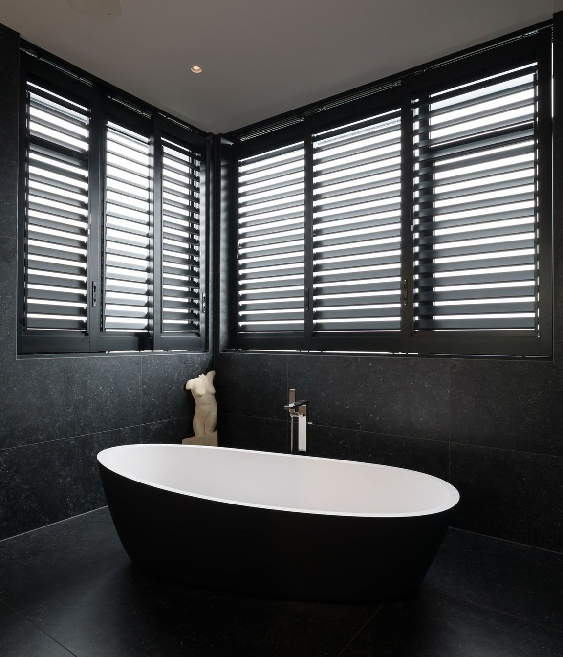 The dramatic black and white bathroom features large-format tiles.