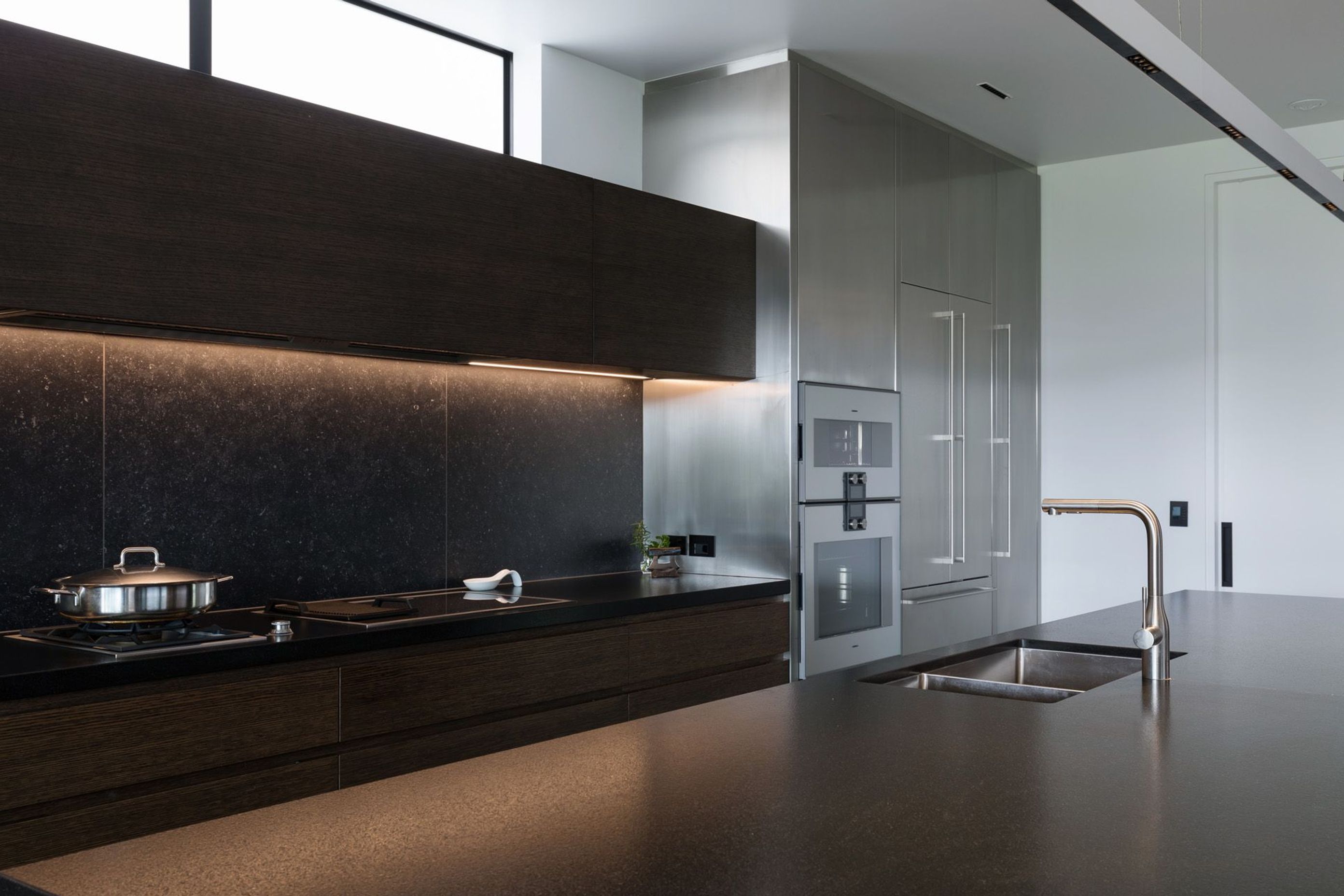 Dark-oak, built-in cabinetry and beautiful honed-black granite benchtops provide a strong contrast against the white walls in the kitchen.