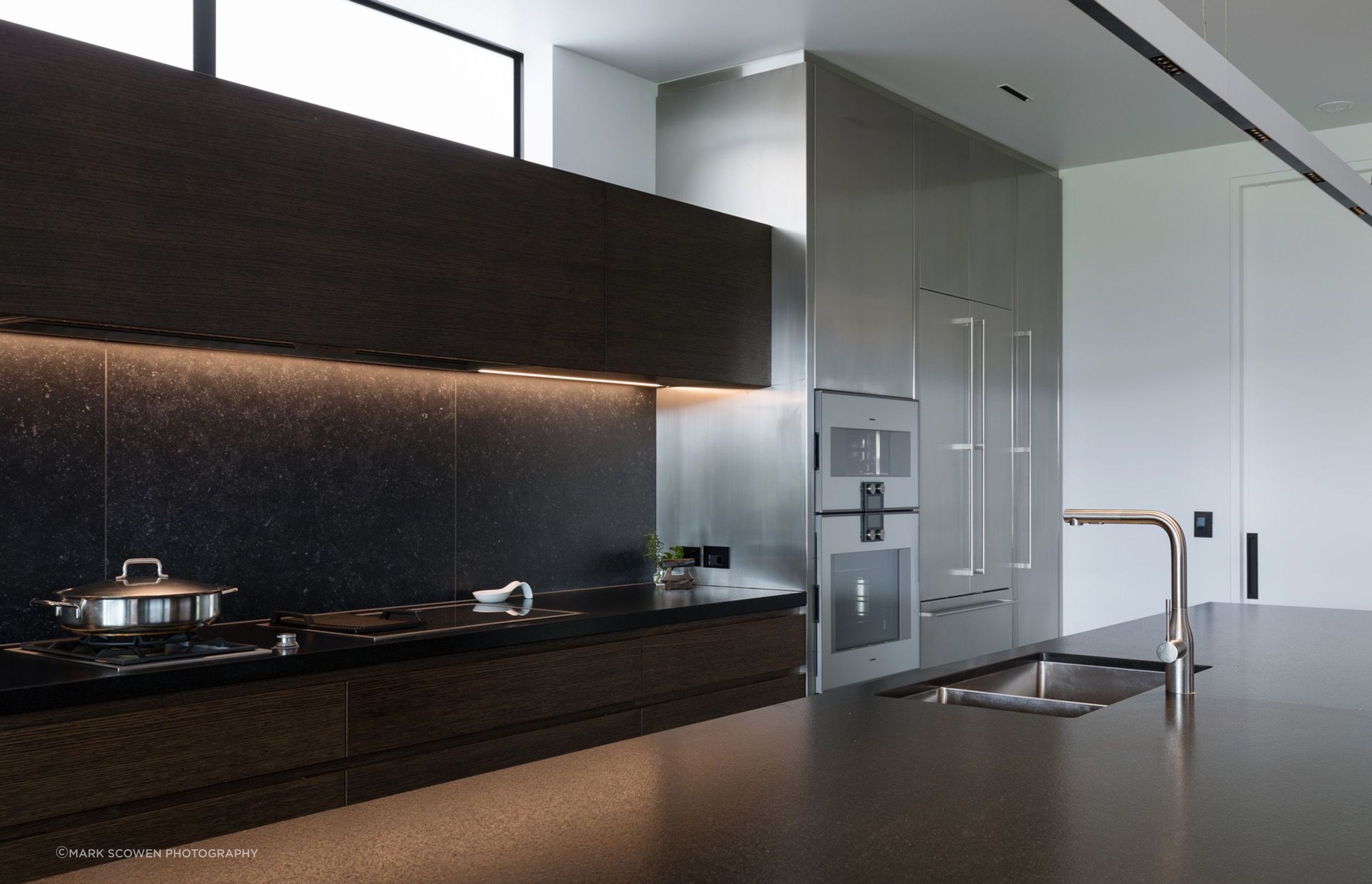 Dark-oak, built-in cabinetry and beautiful honed-black granite benchtops provide a strong contrast against the white walls in the kitchen.