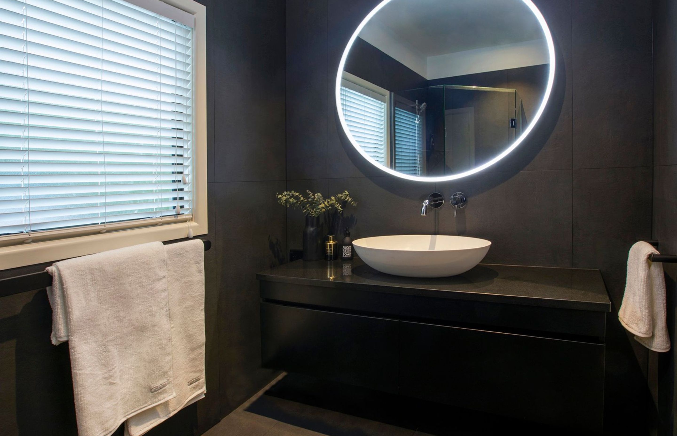 This client also undertook their powder room renovation with us, we flipped the contrast on this space and created a moody atmosphere with the dark tiles and  white accessories to compliment the LED mirror beautifully. The wall-mounted tapware in this van