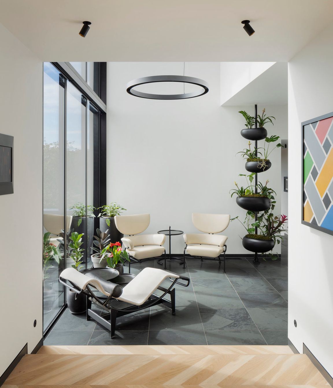 A double height glazed volume with a bridge above serves as a reading room with views across the outdoor spaces and into the living and dining areas.