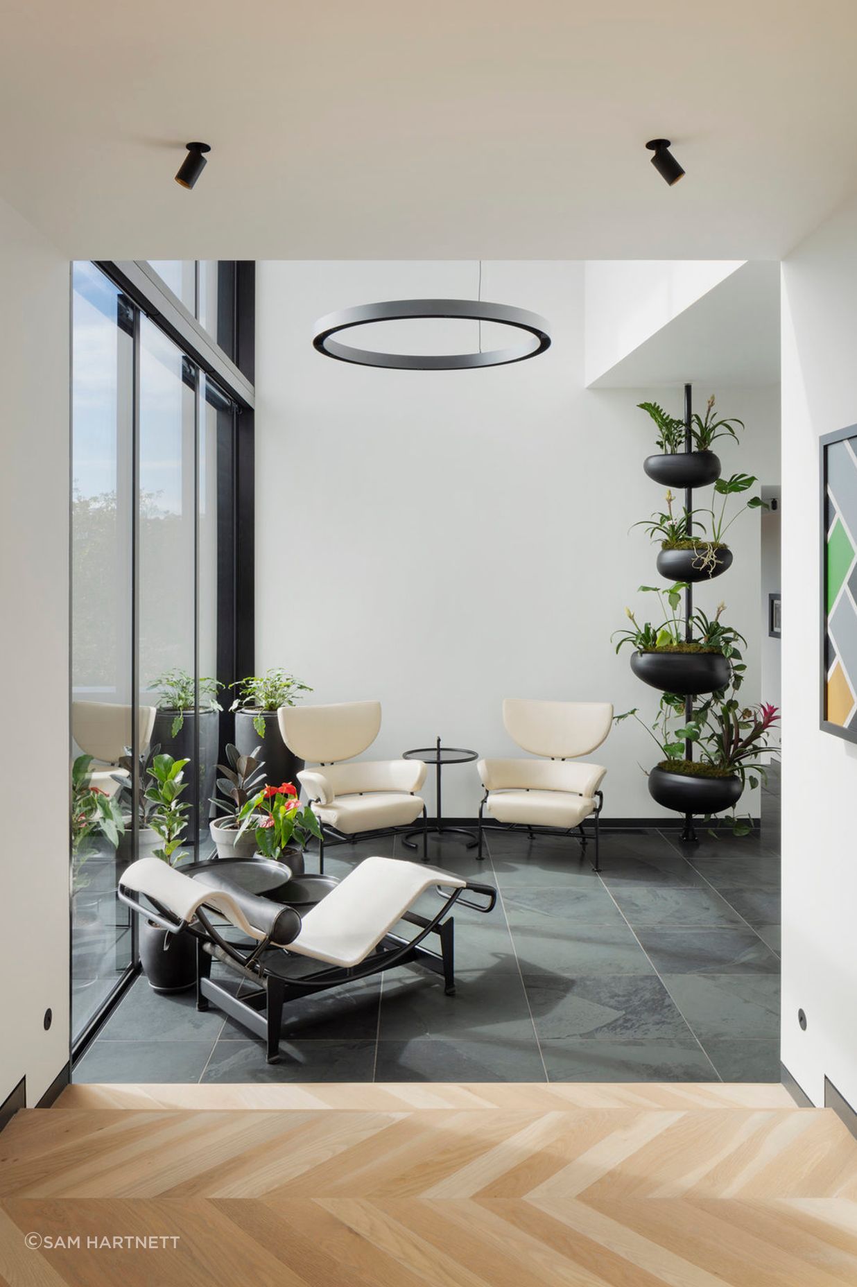A double height glazed volume with a bridge above serves as a reading room with views across the outdoor spaces and into the living and dining areas.