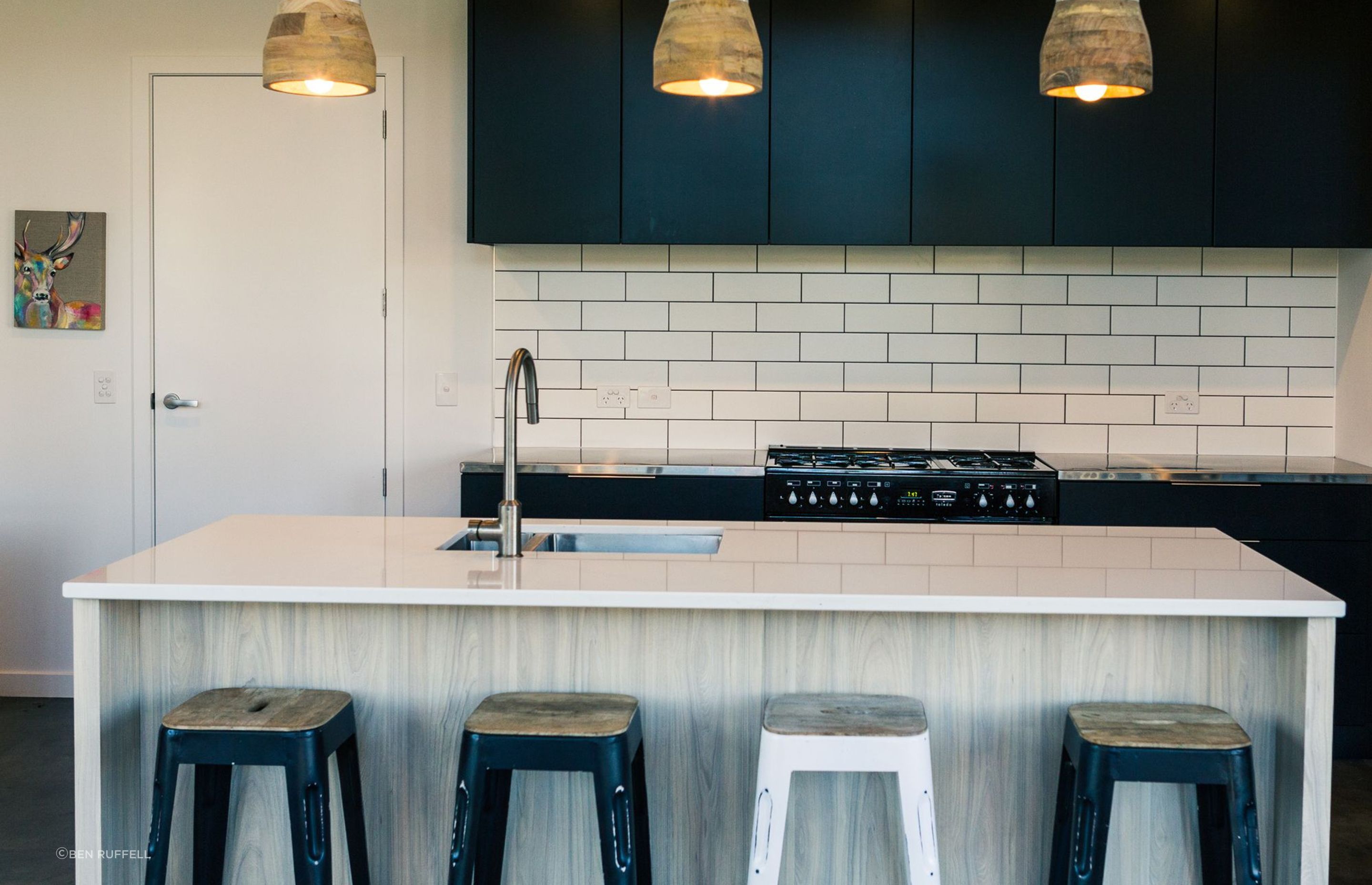 White subway tiles and black cabinetry, along with stone and stainless steel benchtops create a very functional kitchen space.