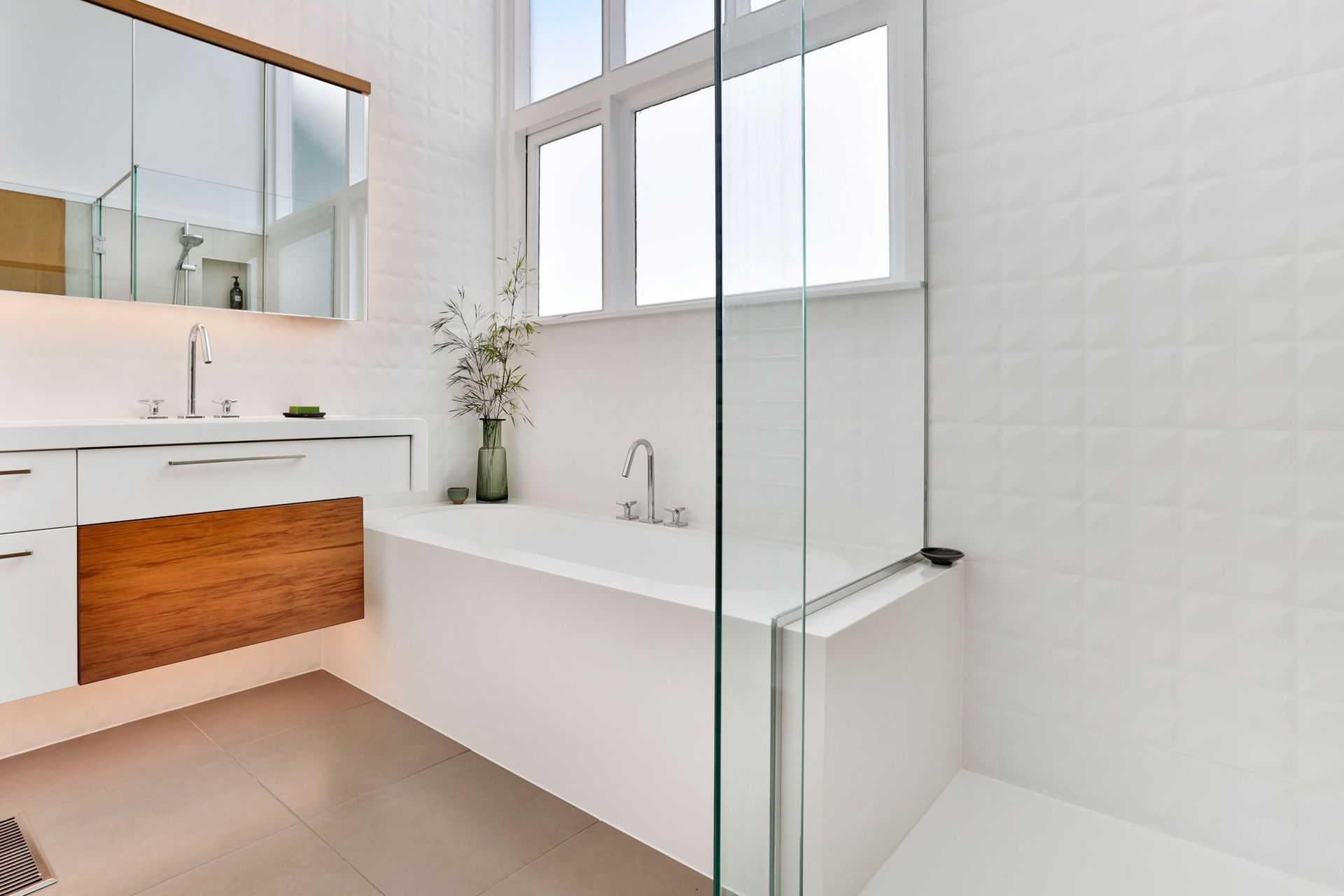 This natural light bathed bathroom delivers a sense of fresh and calm while functioning on a practical level as an easy-clean, monolithic design, seamlessly sealed in Corian. Its geometric tiles, touches of timber and seamless forms, portray a soulful ch