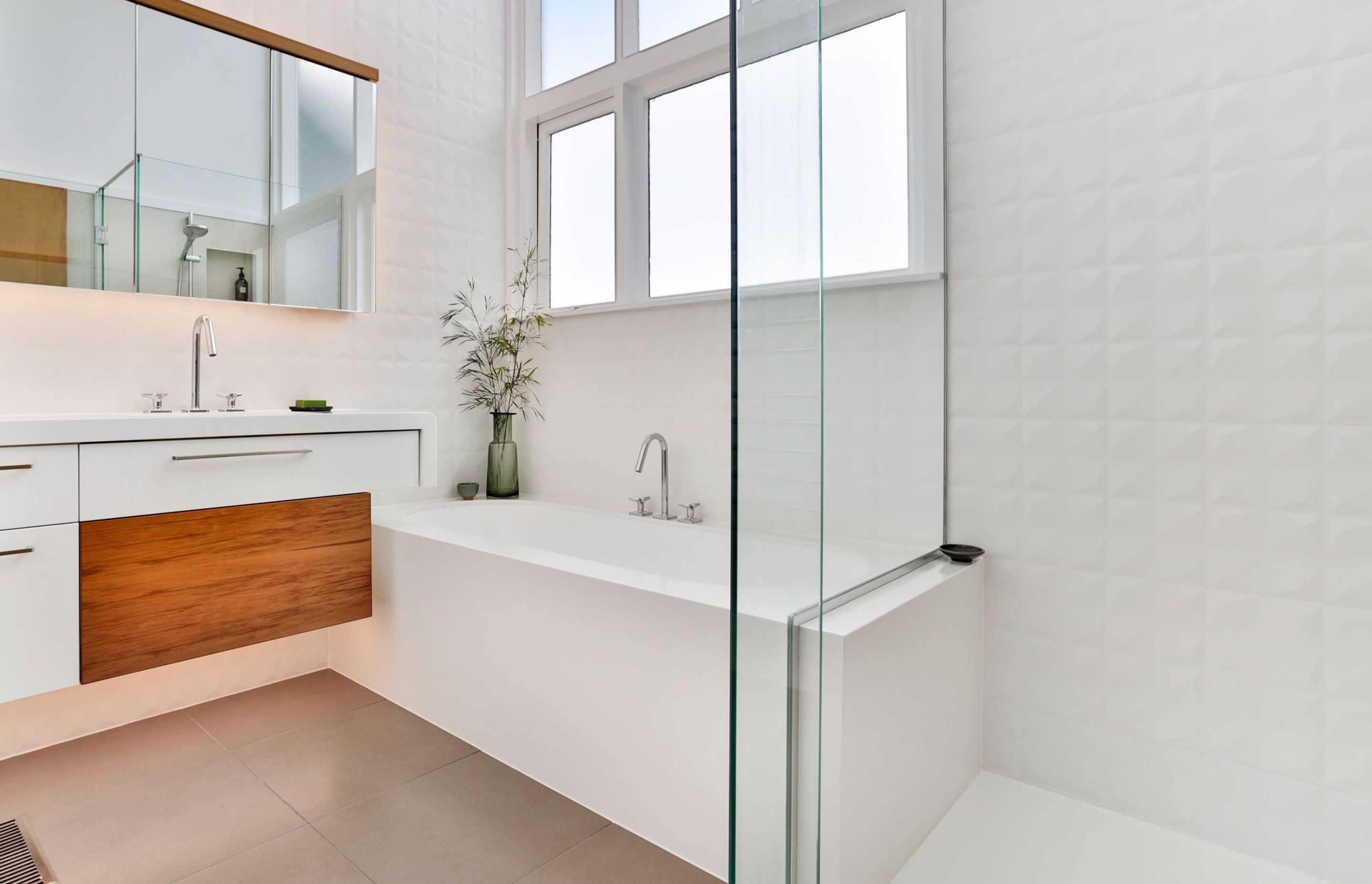 This natural light bathed bathroom delivers a sense of fresh and calm while functioning on a practical level as an easy-clean, monolithic design, seamlessly sealed in Corian.  Its geometric tiles, touches of timber and seamless forms, portray a soulful ch