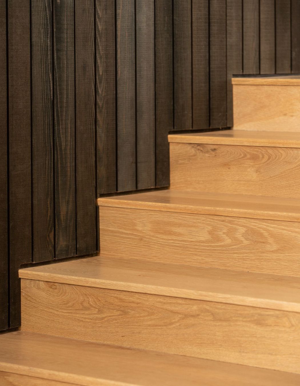 Here, the vertical wall panelling meets the lighter, Tasmanian Oak flooring.