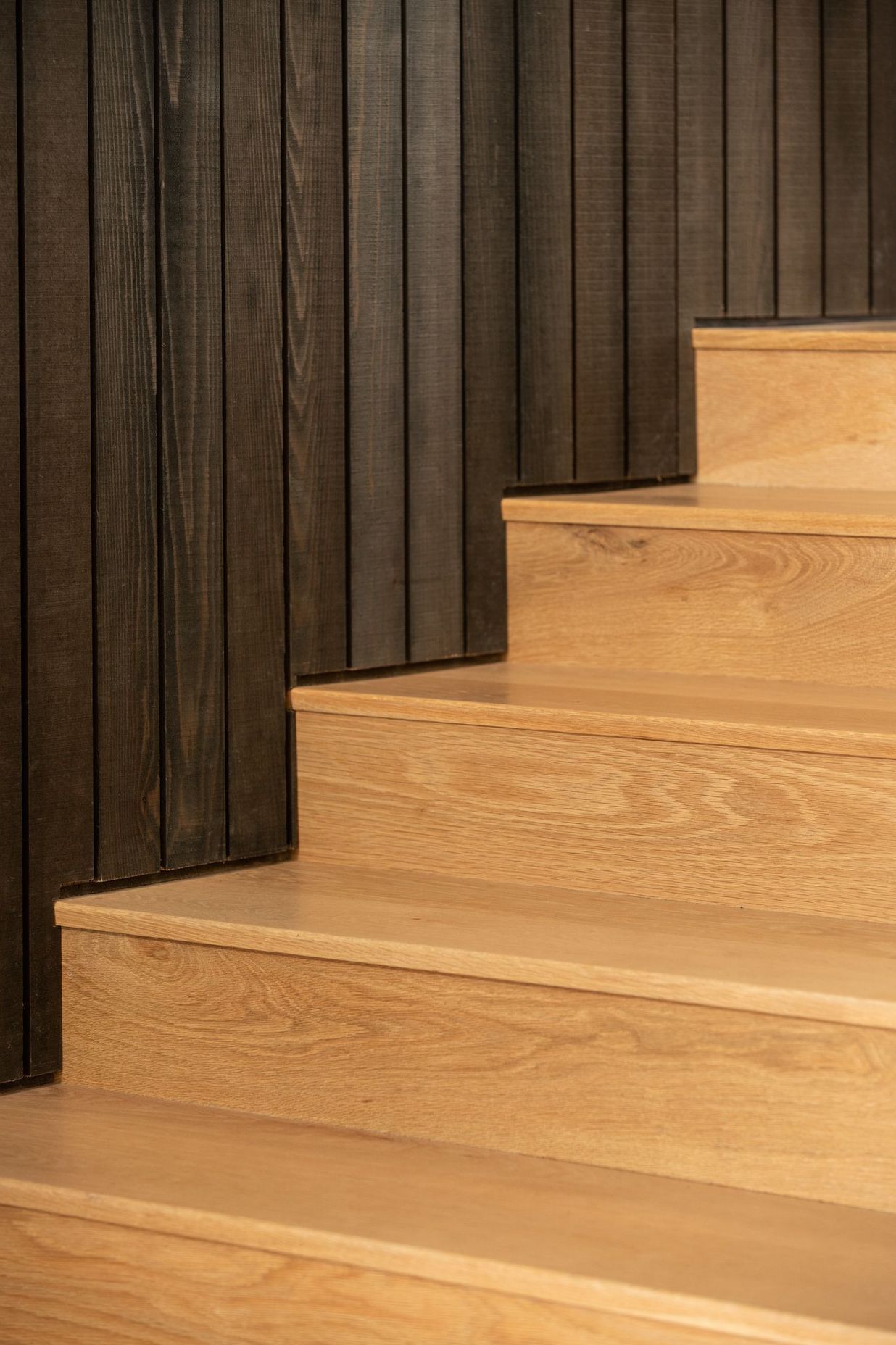 Here, the vertical wall panelling meets the lighter, Tasmanian Oak flooring. 