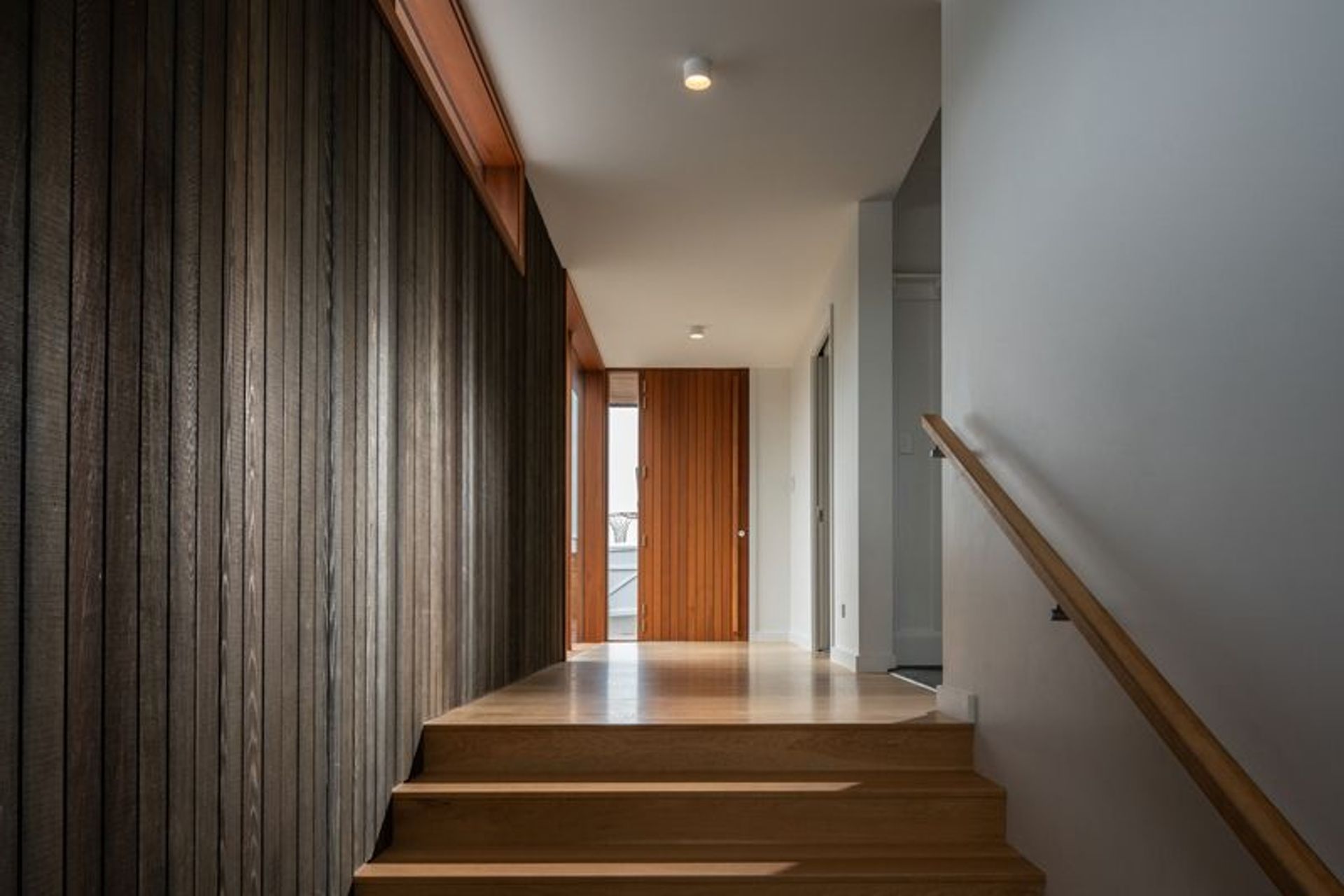 The entrance gallery features dark-stained vertical cedar wall panelling that creates a synergy with the exterior cladding.