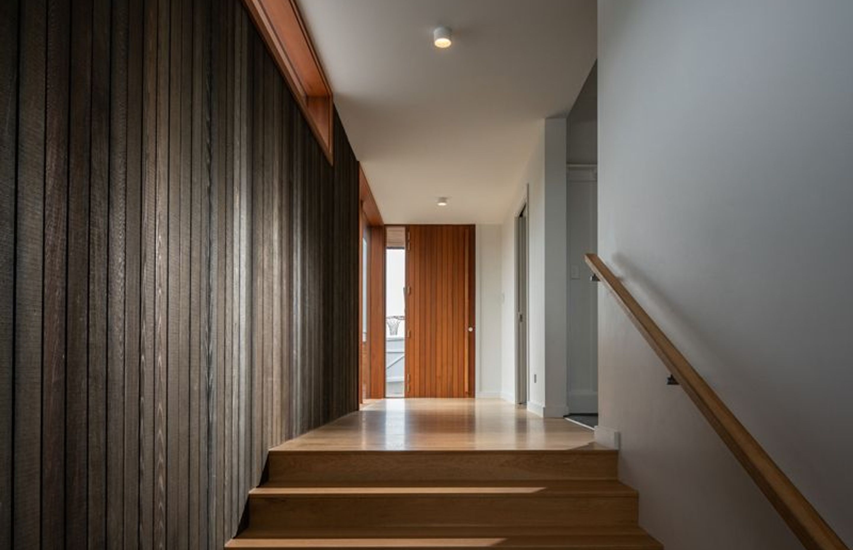 The entrance gallery features dark-stained vertical cedar wall panelling that creates a synergy with the exterior cladding.