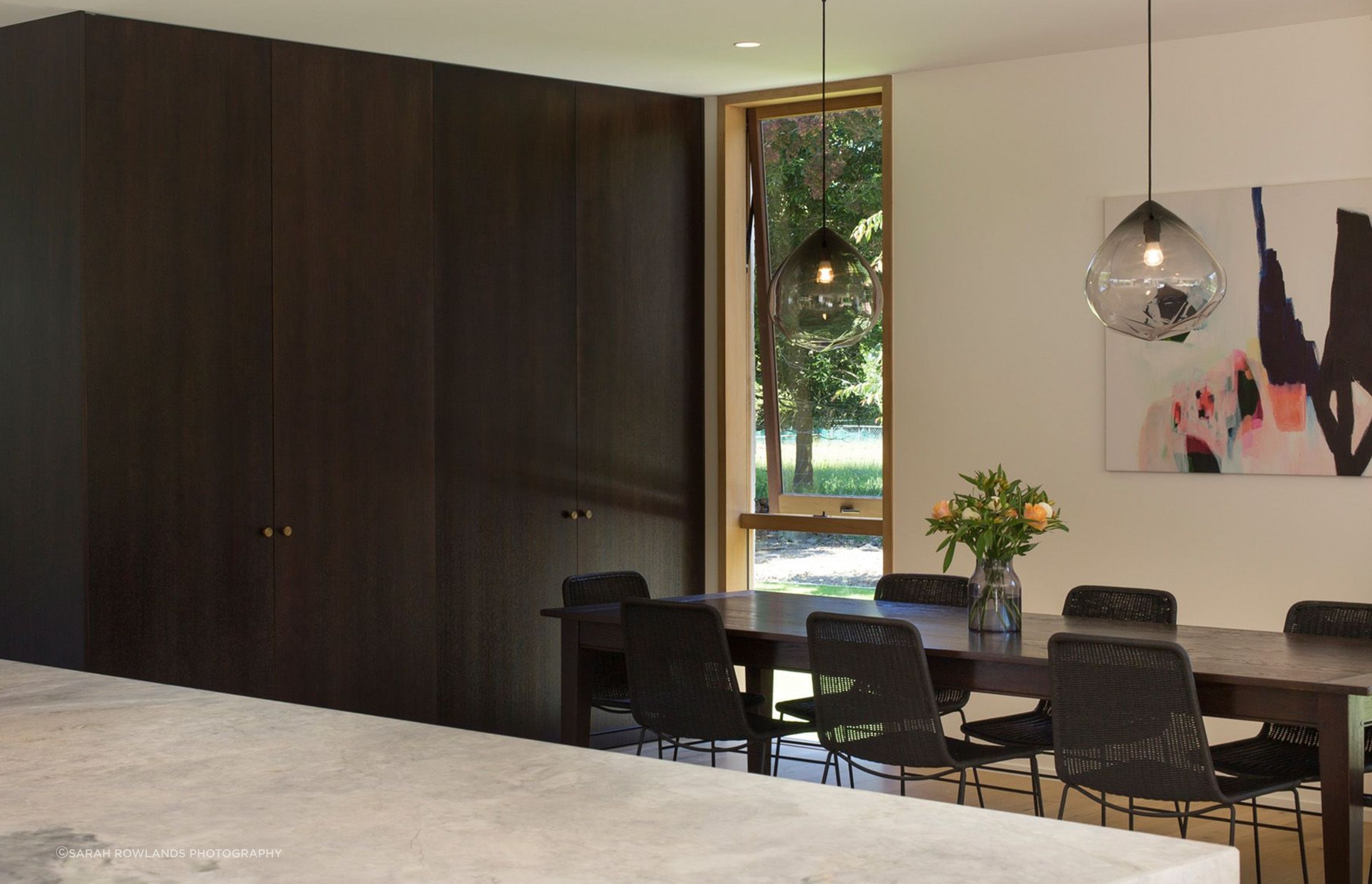 The dining area features floor-to-ceiling cabinetry to match the vintage oak dining table and the kitchen cabinetry.