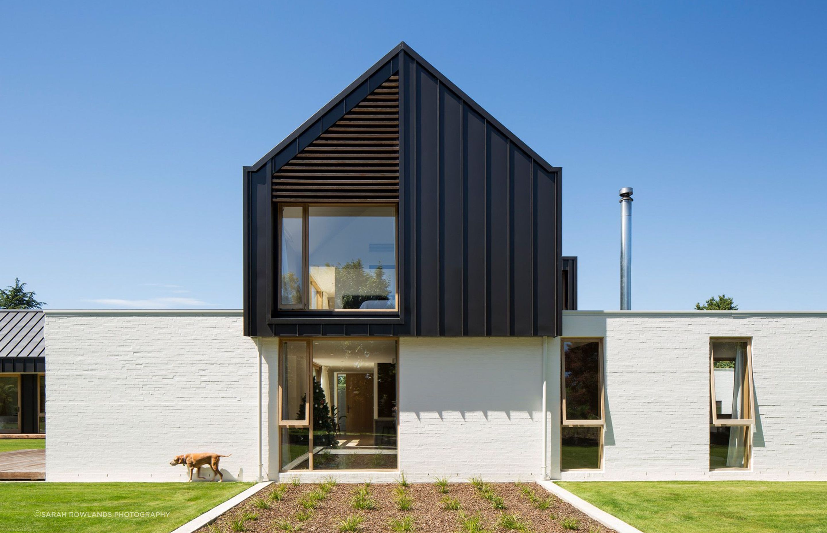 Vertical windows break up rhythm along the edge of the main living area. The upper storey glazing features a cedar screen to bring dappled light into the master suite.