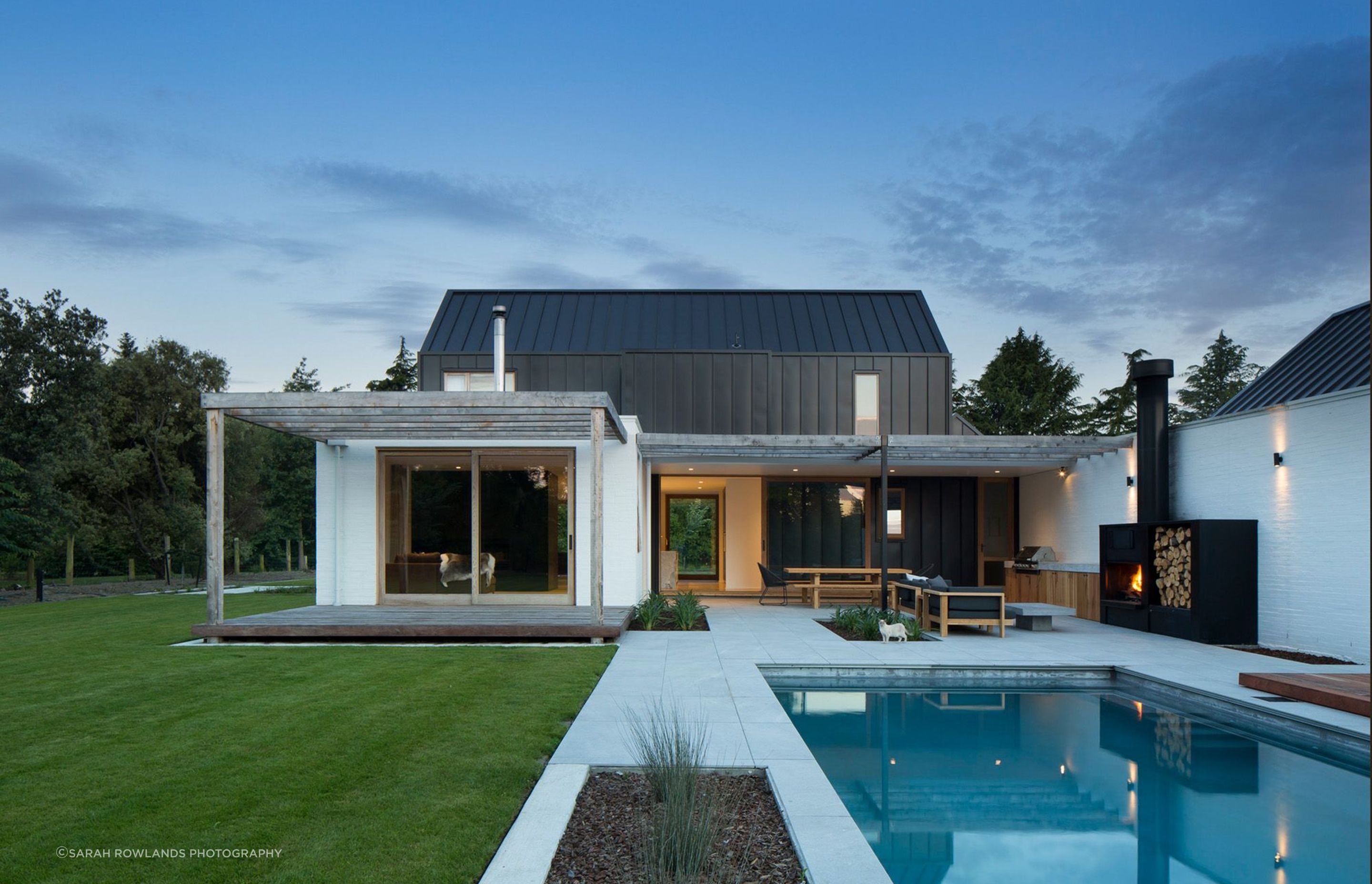 The swimming pool/entertaining space at twilight. The fireplace features built-in wood storage.
