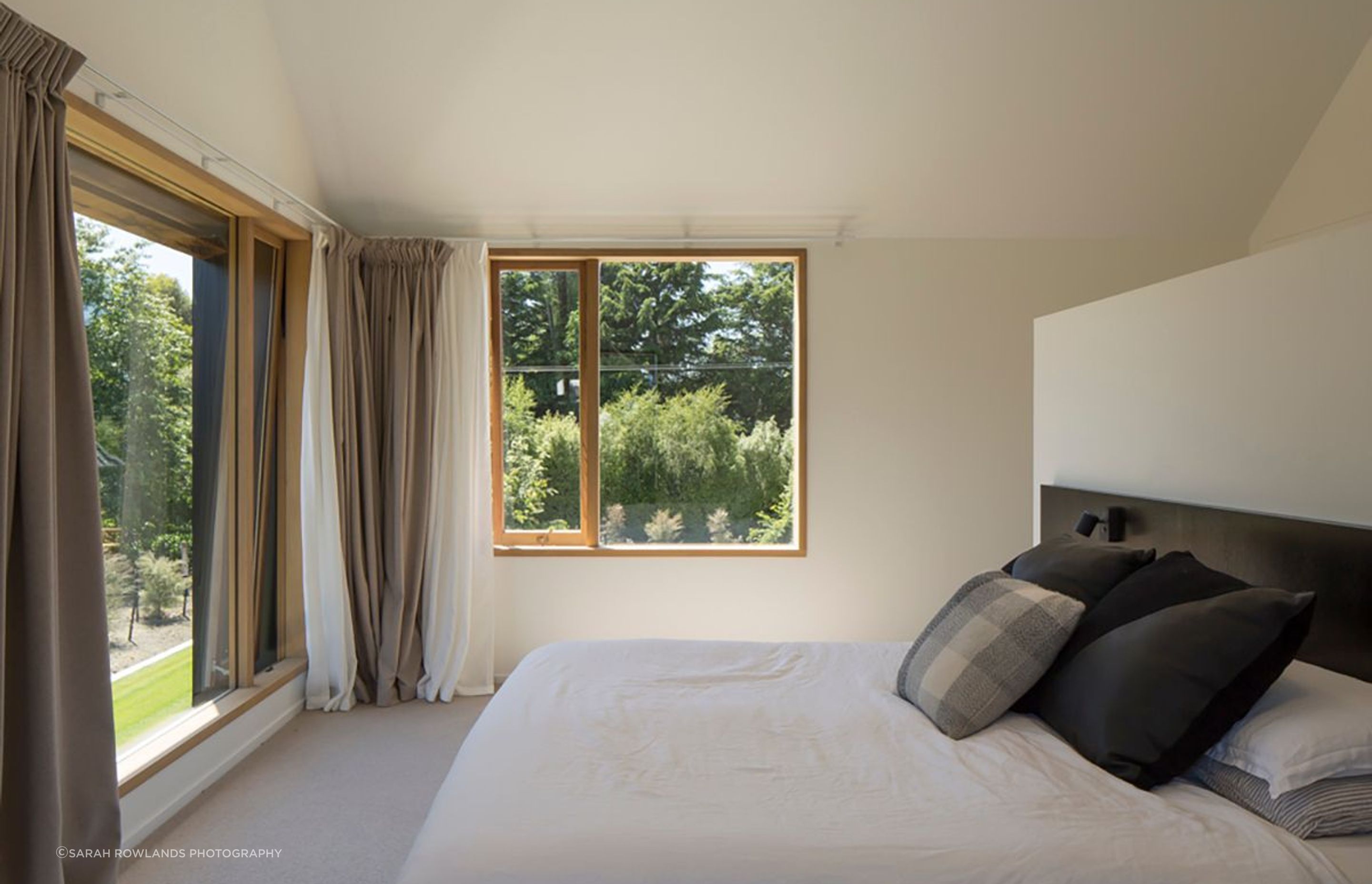 The master bedroom features a custom-built headboard, wardrobe/room divider and a double layer of curtains in wool and sheer fabrics.