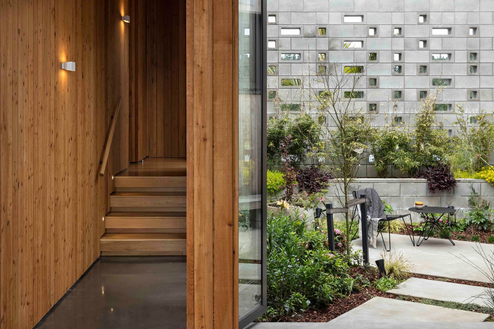 The main living space steps down from the bedroom spaces and features a concrete floor; the external courtyard is entirely enclosed and creates privacy from the road.