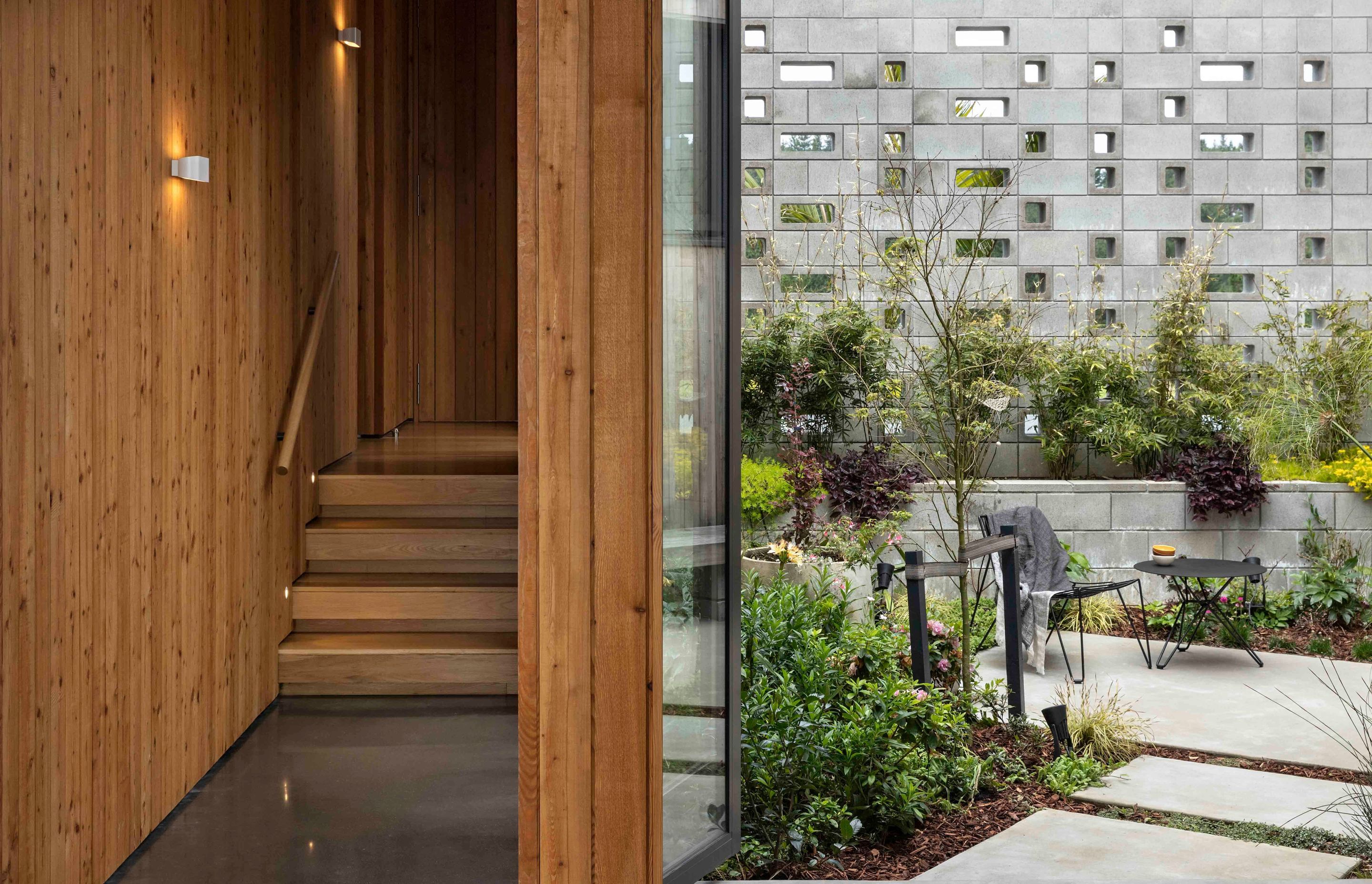 The main living space steps down from the bedroom spaces and features a concrete floor; the external courtyard is entirely enclosed and creates privacy from the road.