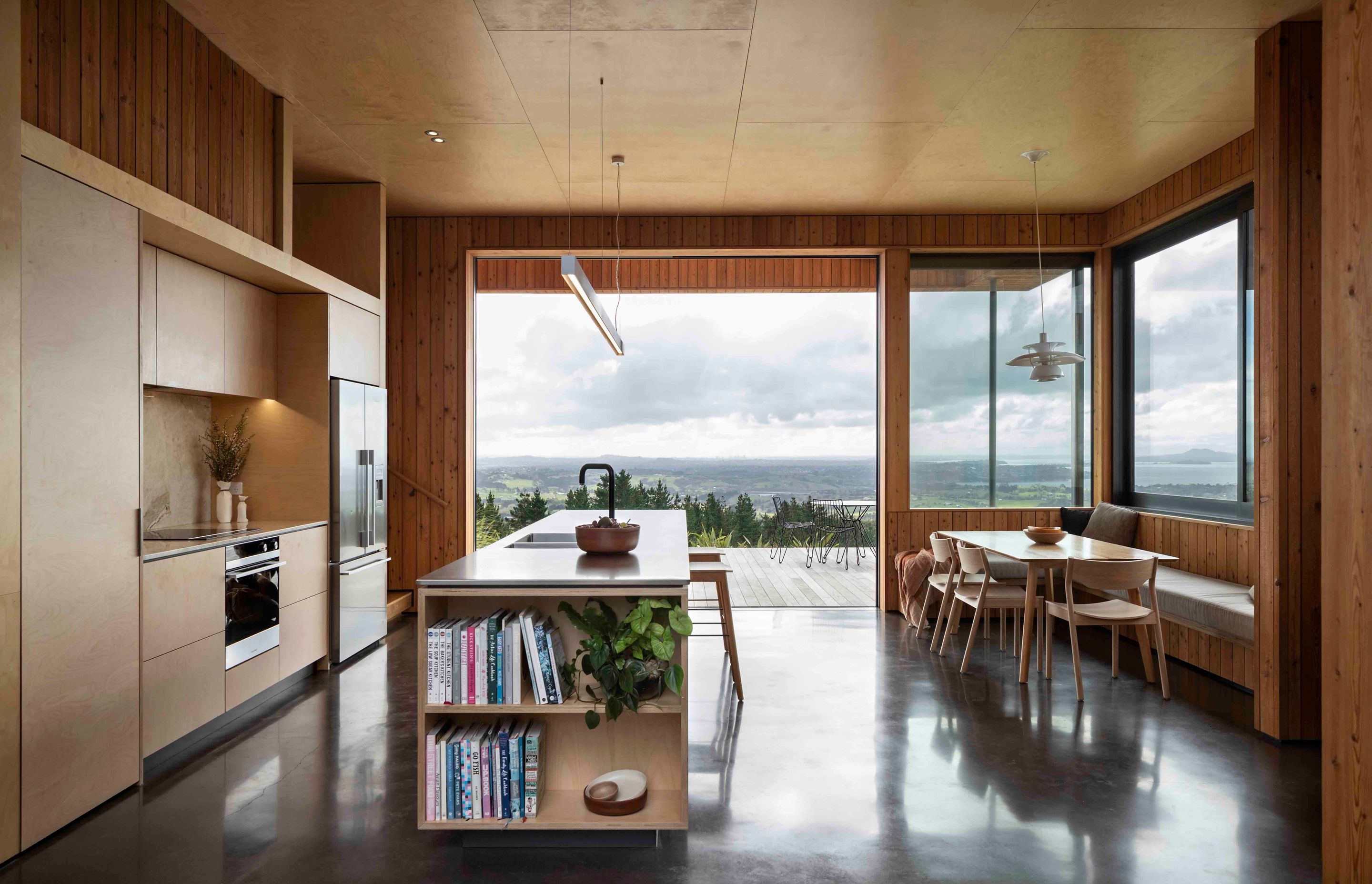 Birch plywood lines the ceiling of the kitchen, creating a biophilic tie to the outdoor spaces.
