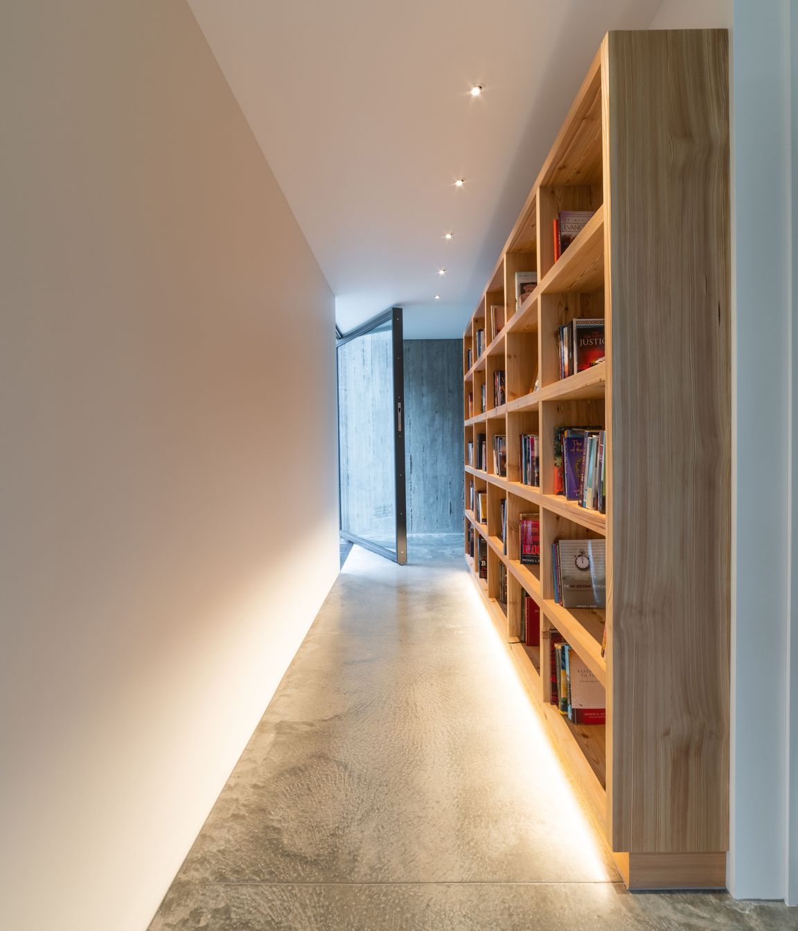 The glass entry door allows for seamless sightlines throughout the house to the cliff face behind.