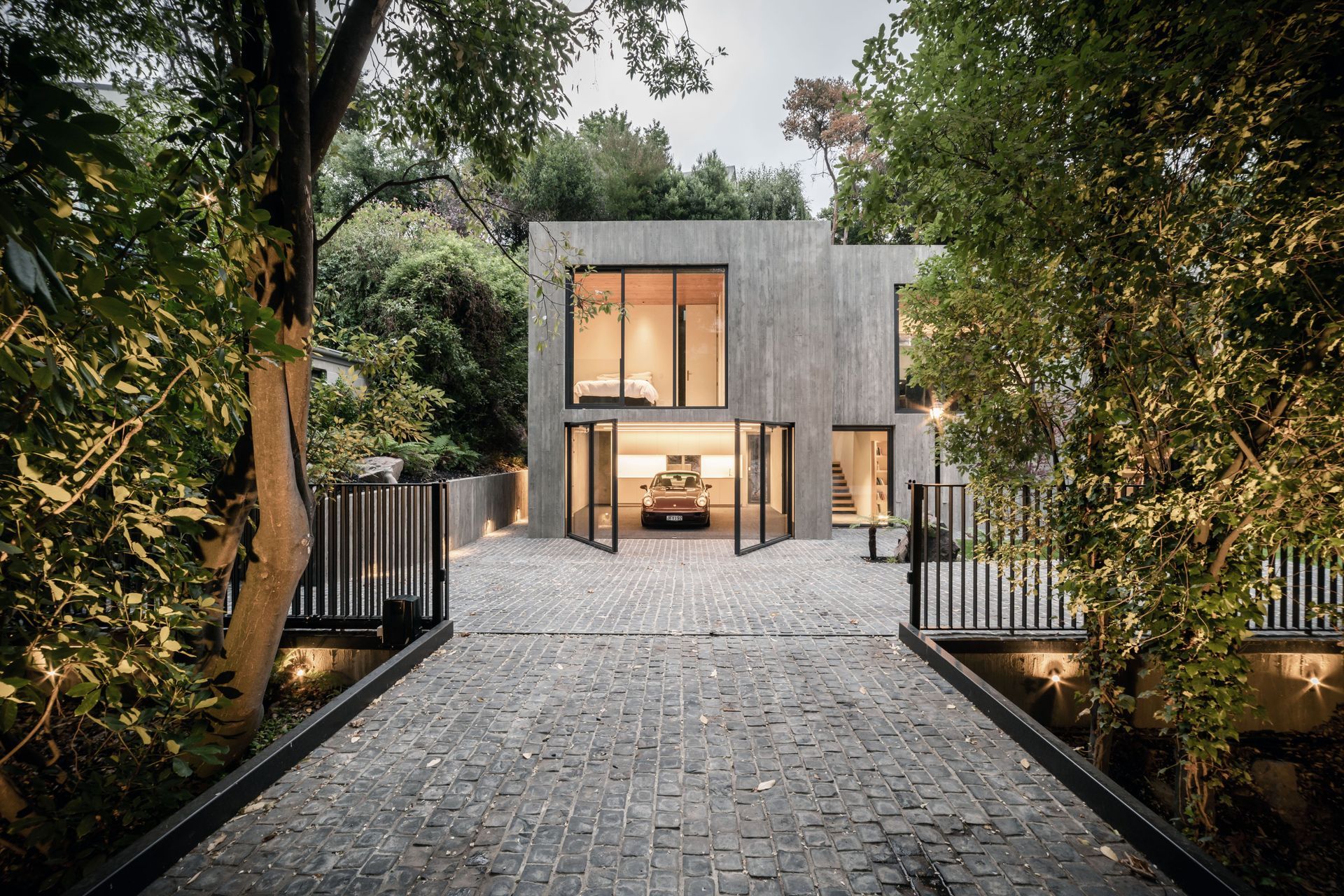 The extensive glazing extends to the garaging and front door to the right of the garage, offering a transparency to the solid concrete form.