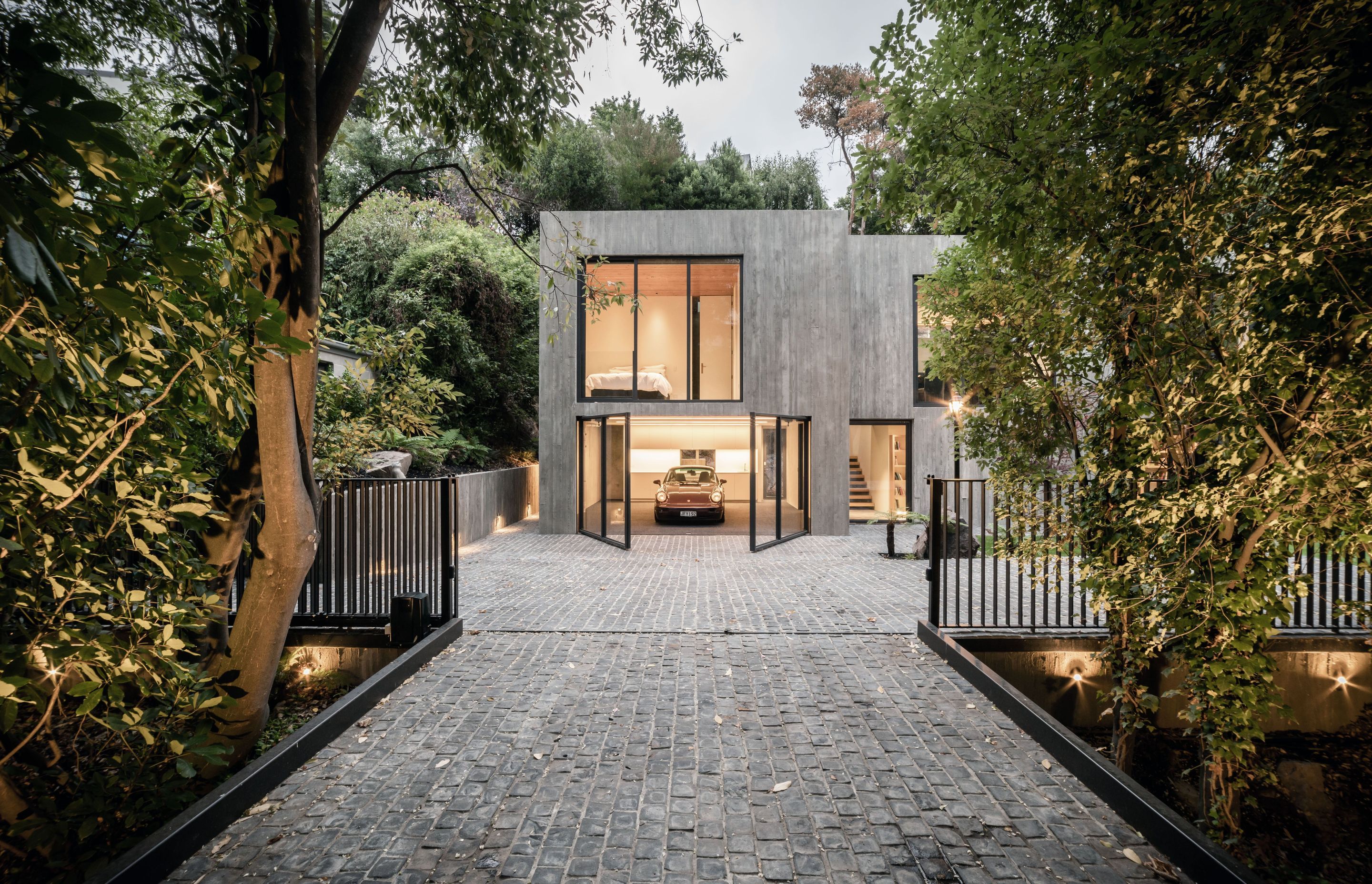 The extensive glazing extends to the garaging and front door to the right of the garage, offering a transparency to the solid concrete form.