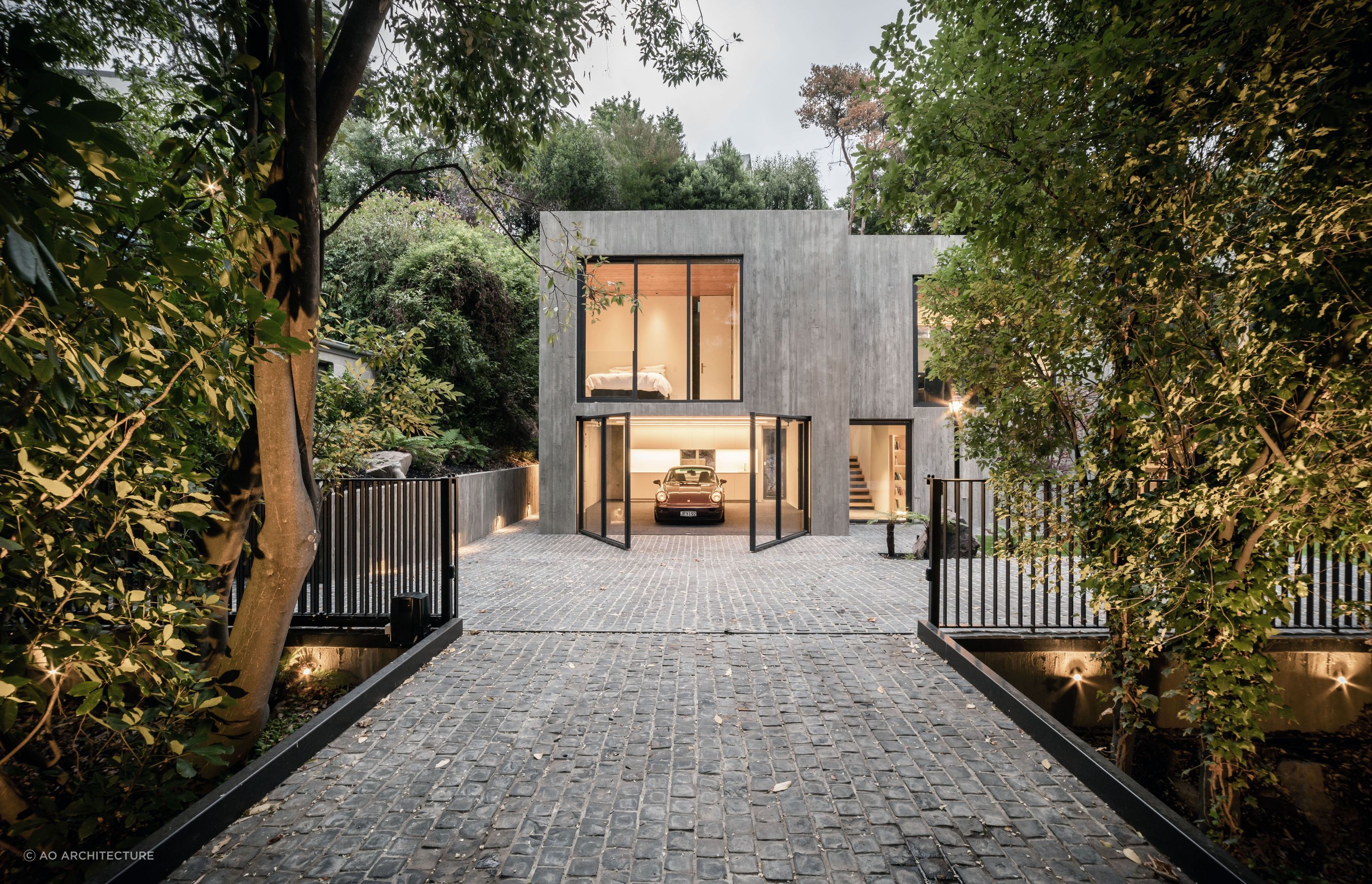 The extensive glazing extends to the garaging and front door to the right of the garage, offering a transparency to the solid concrete form.
