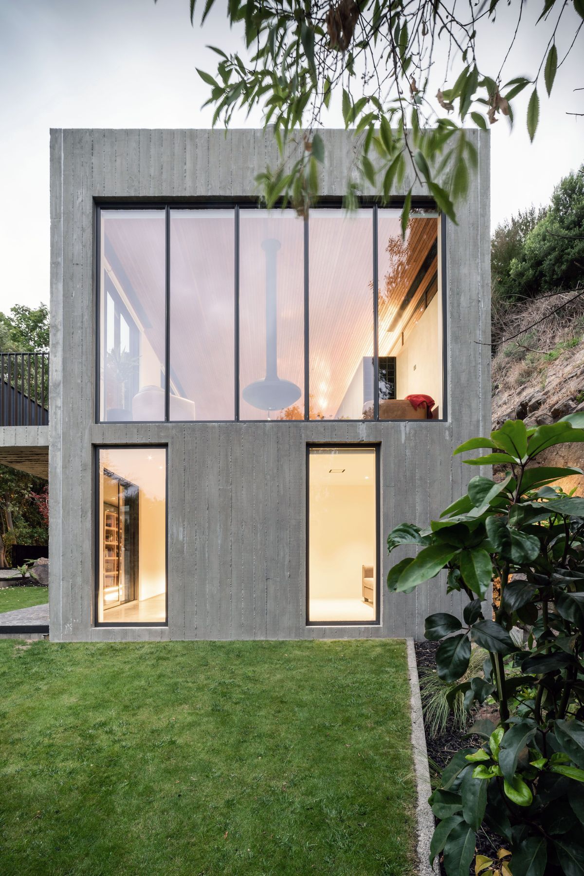 A suspended fire hangs in the centre of the main living room window, from which views down the valley, over Christchurch and to the Southern Alps beyond are captured.