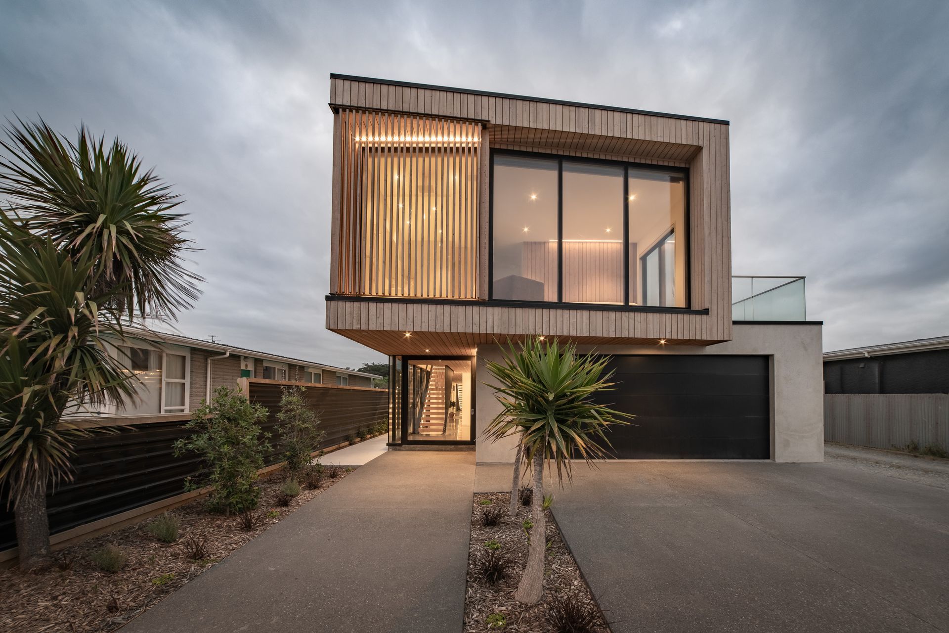 The upper storey is cantilevered out creating an alcove over the striking entrance area which is defined by a glazed, steel-framed door.
