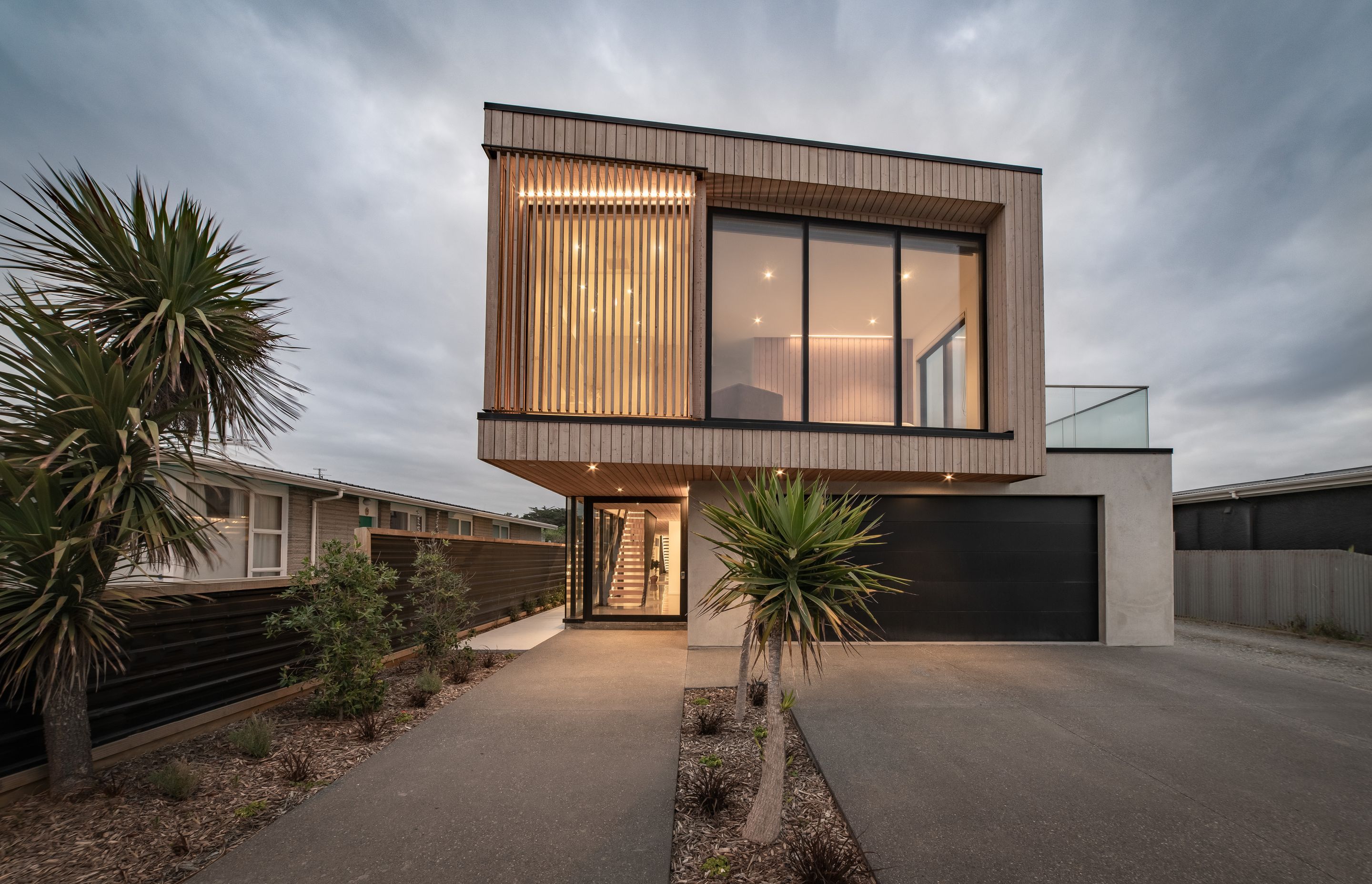 The upper storey is cantilevered out creating an alcove over the striking entrance area which is defined by a glazed, steel-framed door.