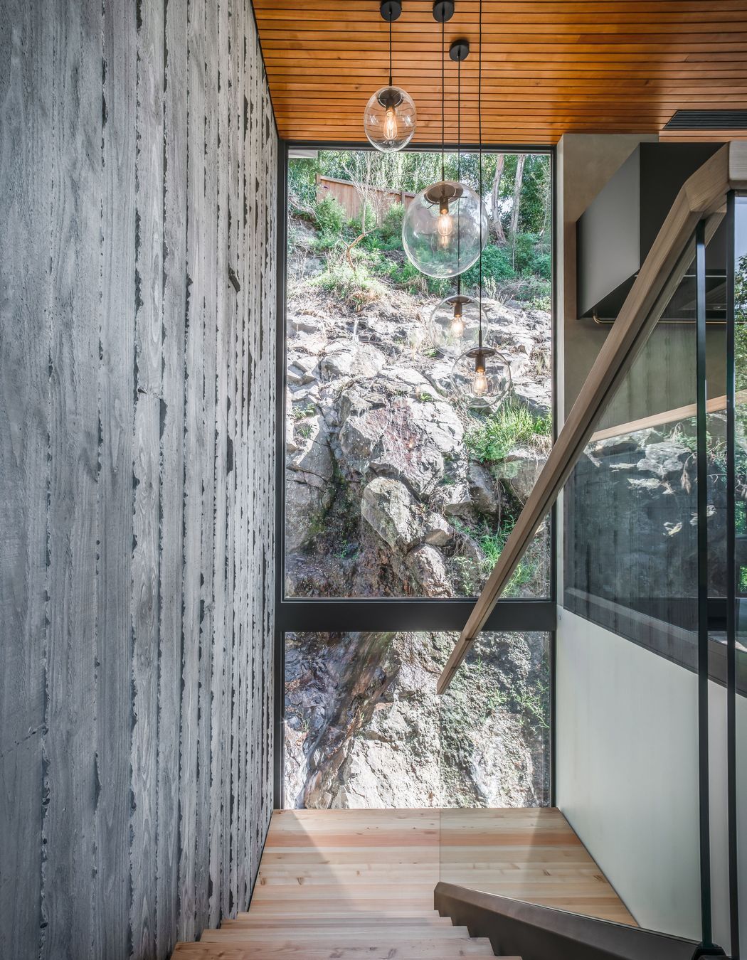 Here, double height glazing offers a confronting view of the rugged cliff face that defines the site.