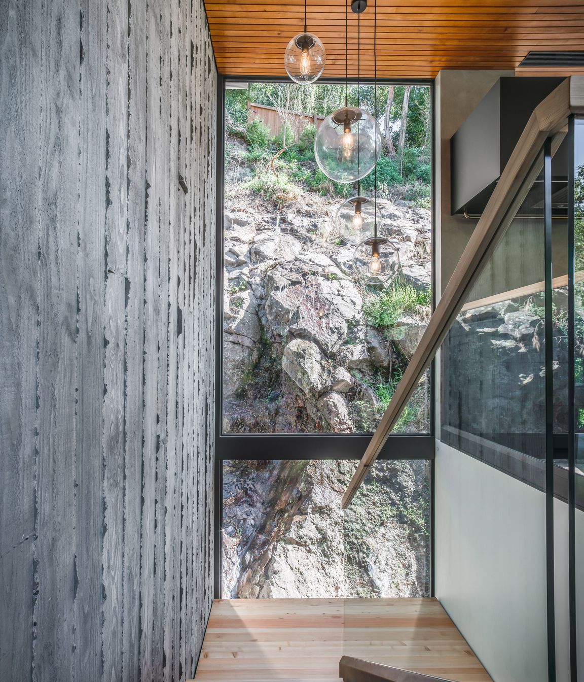 Here, double height glazing offers a confronting view of the rugged cliff face that defines the site.