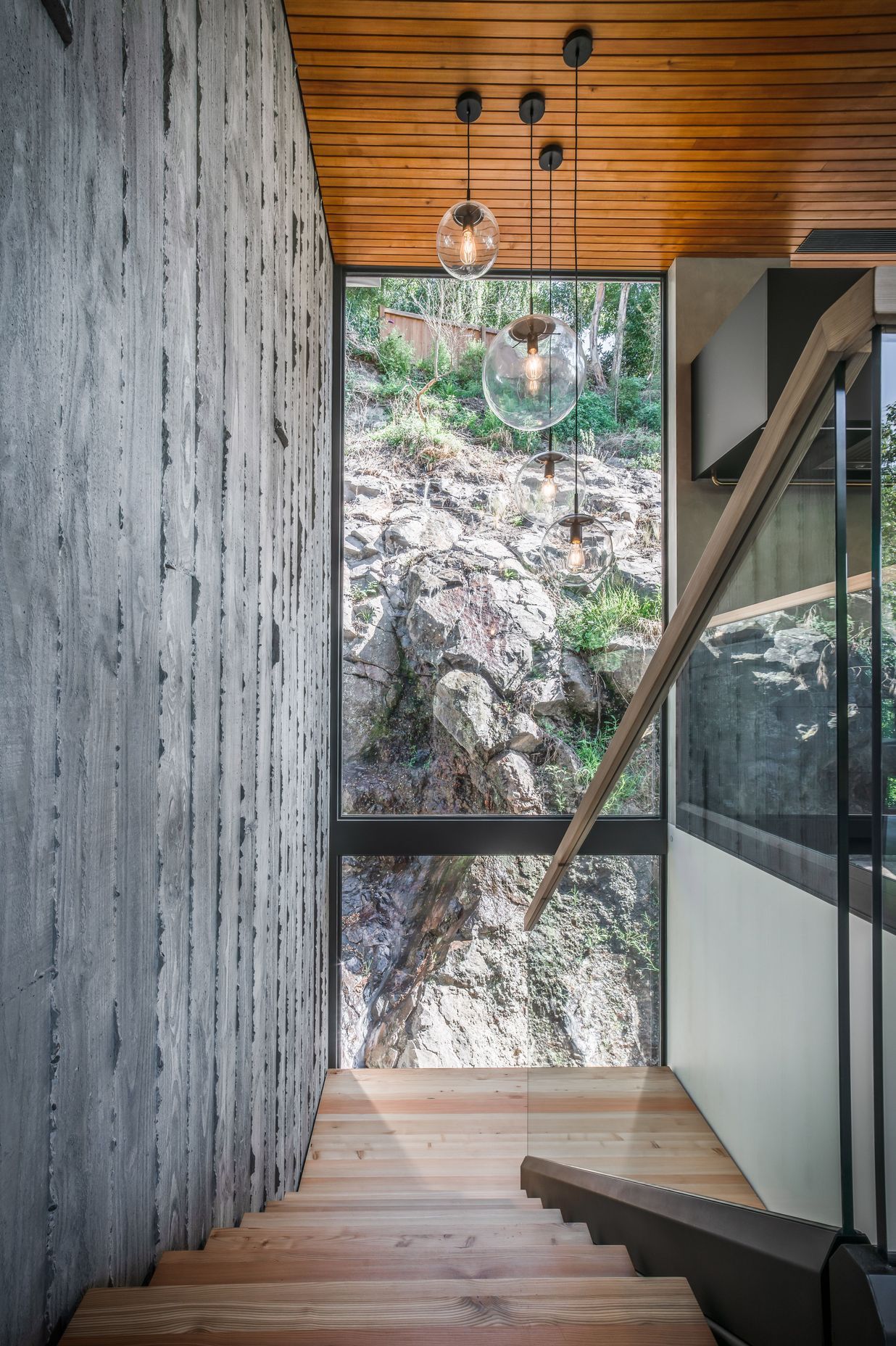 Here, double height glazing offers a confronting view of the rugged cliff face that defines the site.