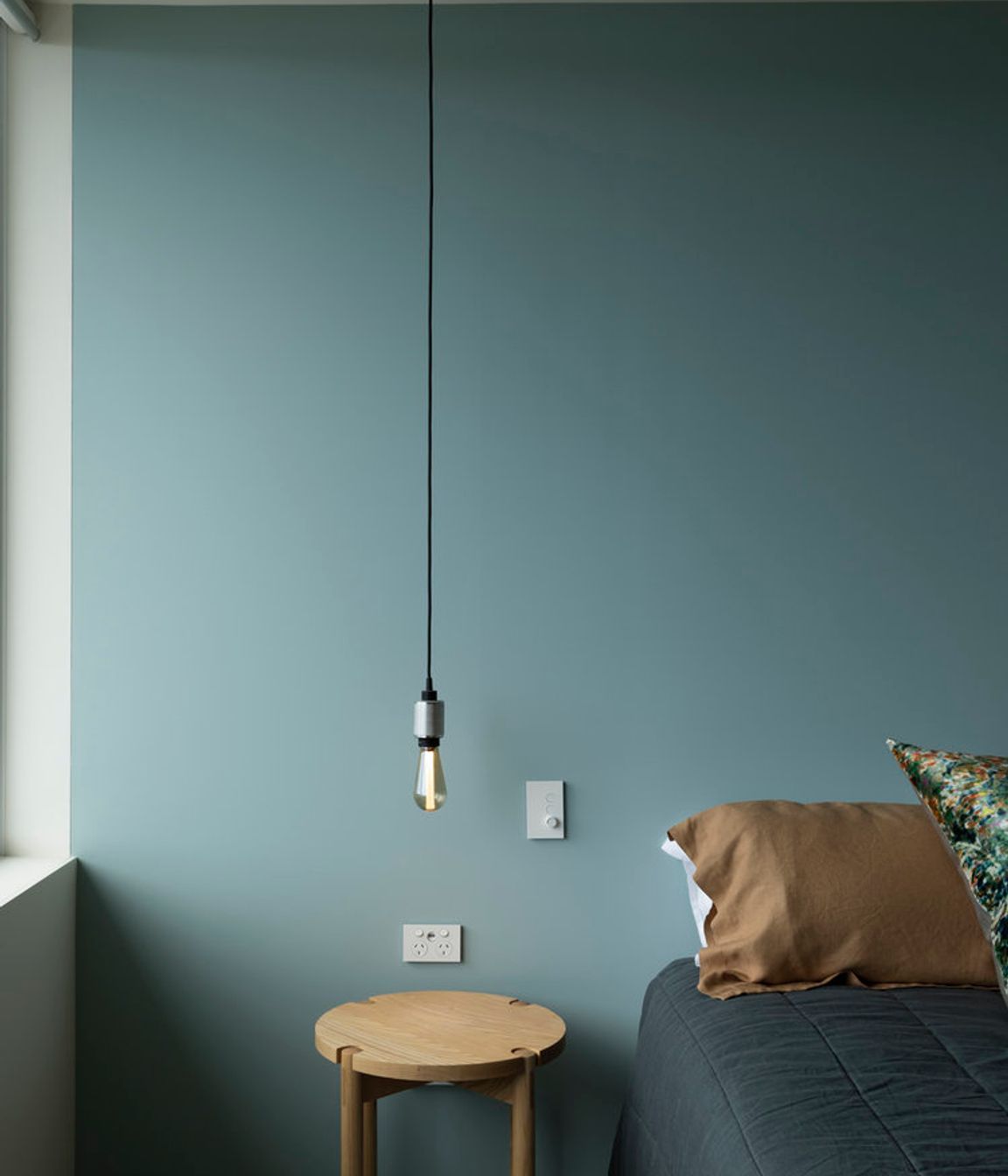A simple low-hanging lightbulb provides bedside lighting.