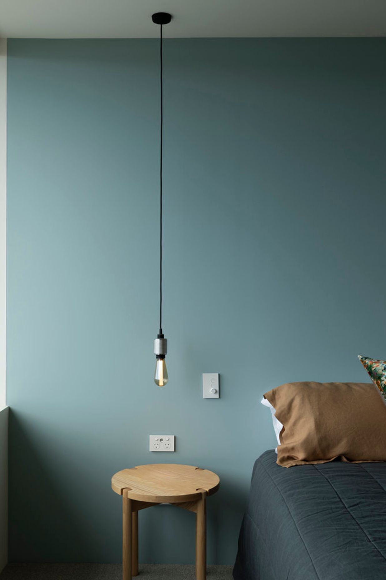 A simple low-hanging lightbulb provides bedside lighting.