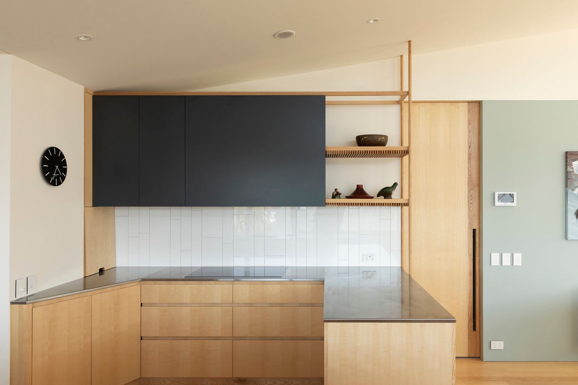 A timeless palette of pale American ash cabinetry and flooring contrasts the white tiled backsplash and charcoal top cupboards and is complemented by soft green walls.