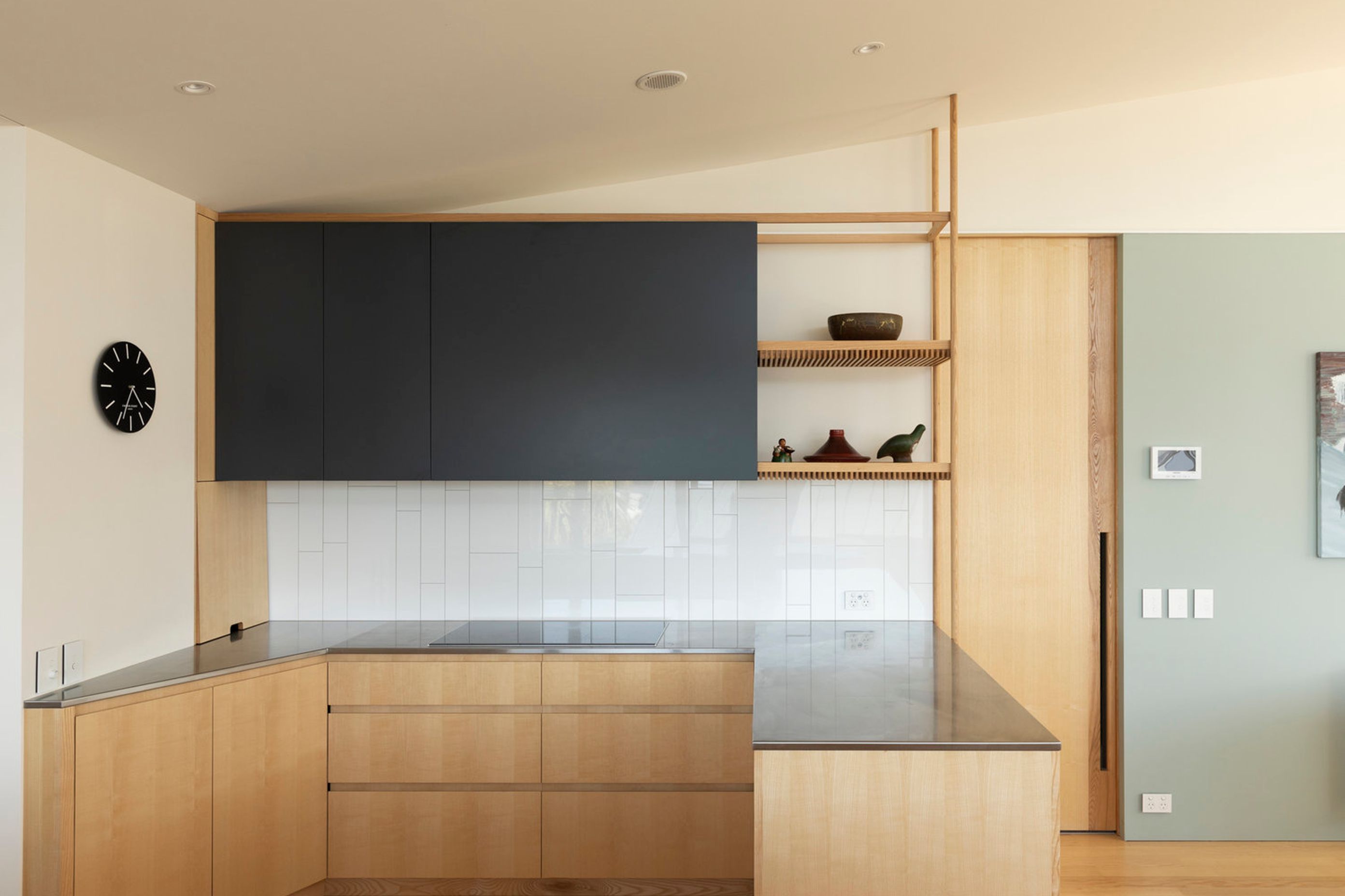 A timeless palette of pale American ash cabinetry and flooring contrasts the white tiled backsplash and charcoal top cupboards and is complemented by soft green walls.