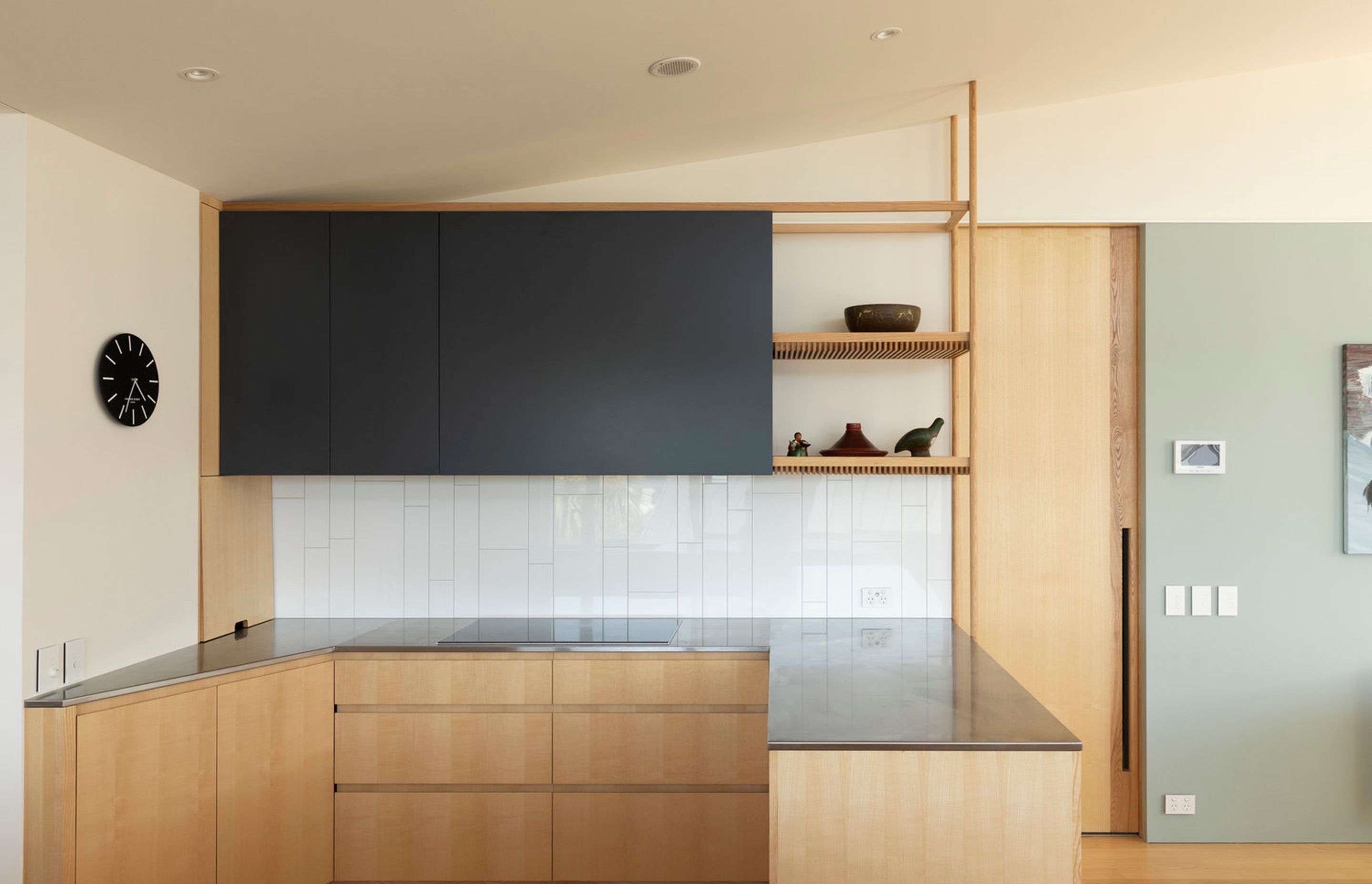 A timeless palette of pale American ash cabinetry and flooring contrasts the white tiled backsplash and charcoal top cupboards and is complemented by soft green walls.