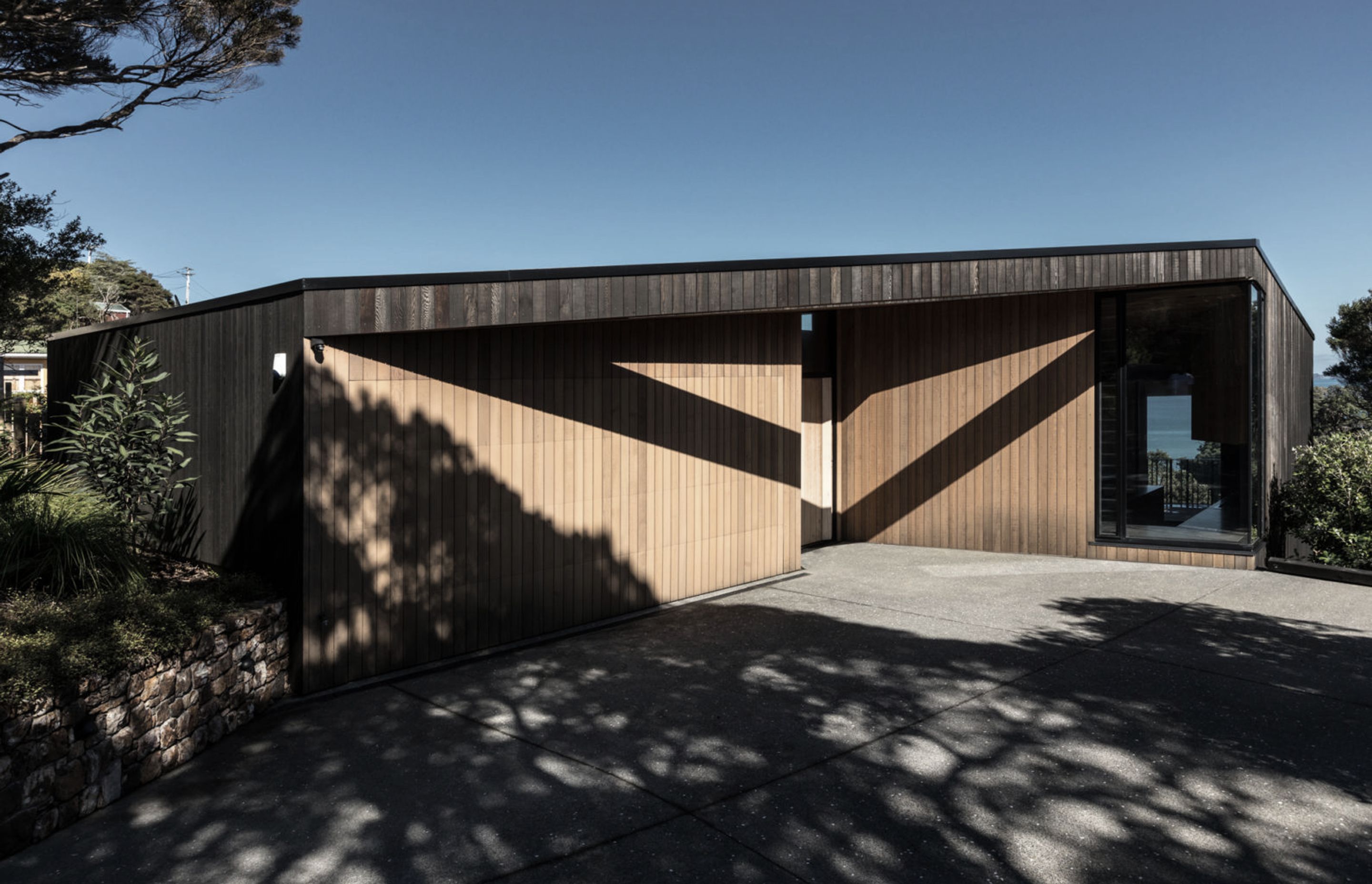 The house reads as a recessive, yet partially exposed, rock-like form.