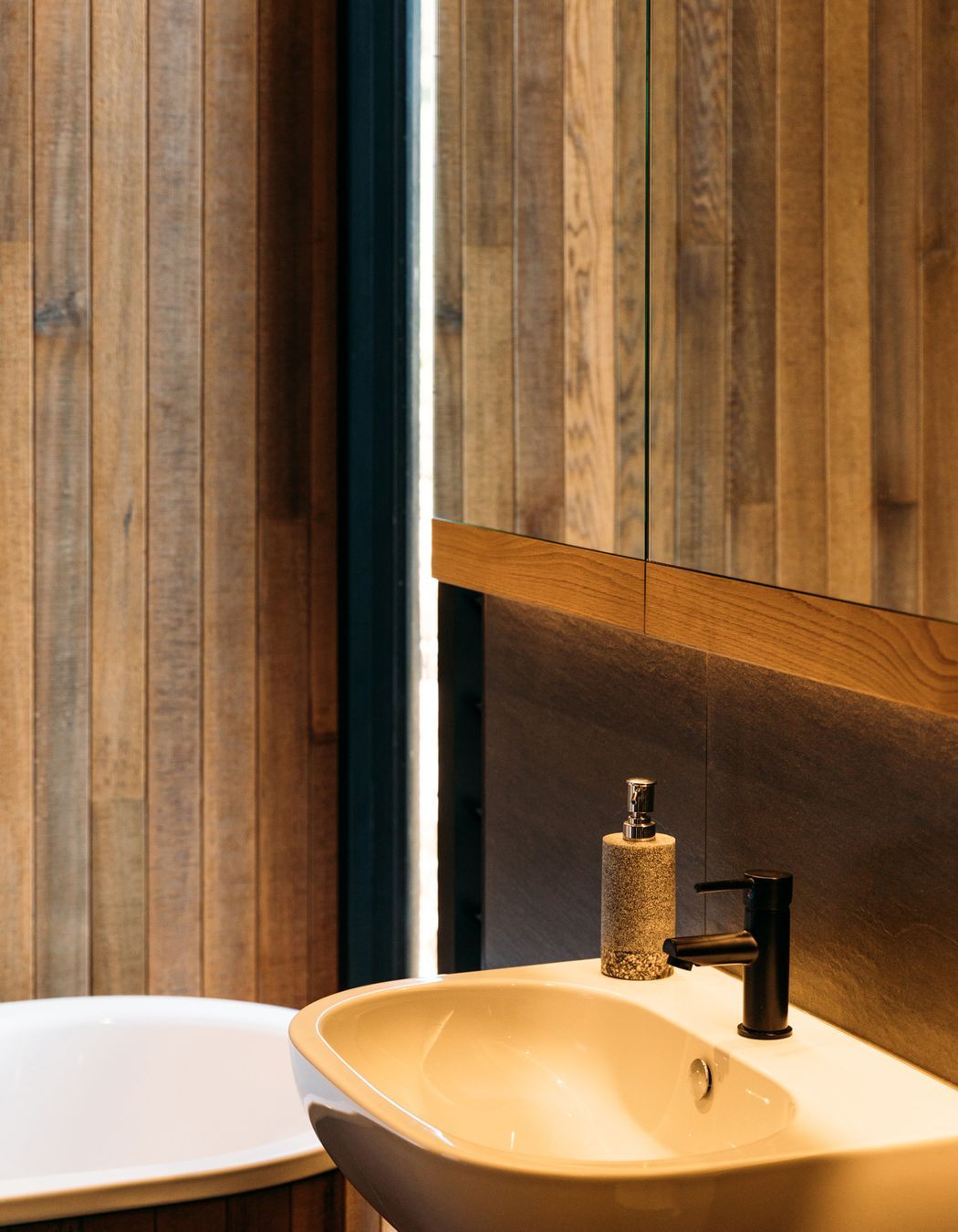 Oahu matt porcelain tiles add textural contrast to the cedar in the main bathroom.