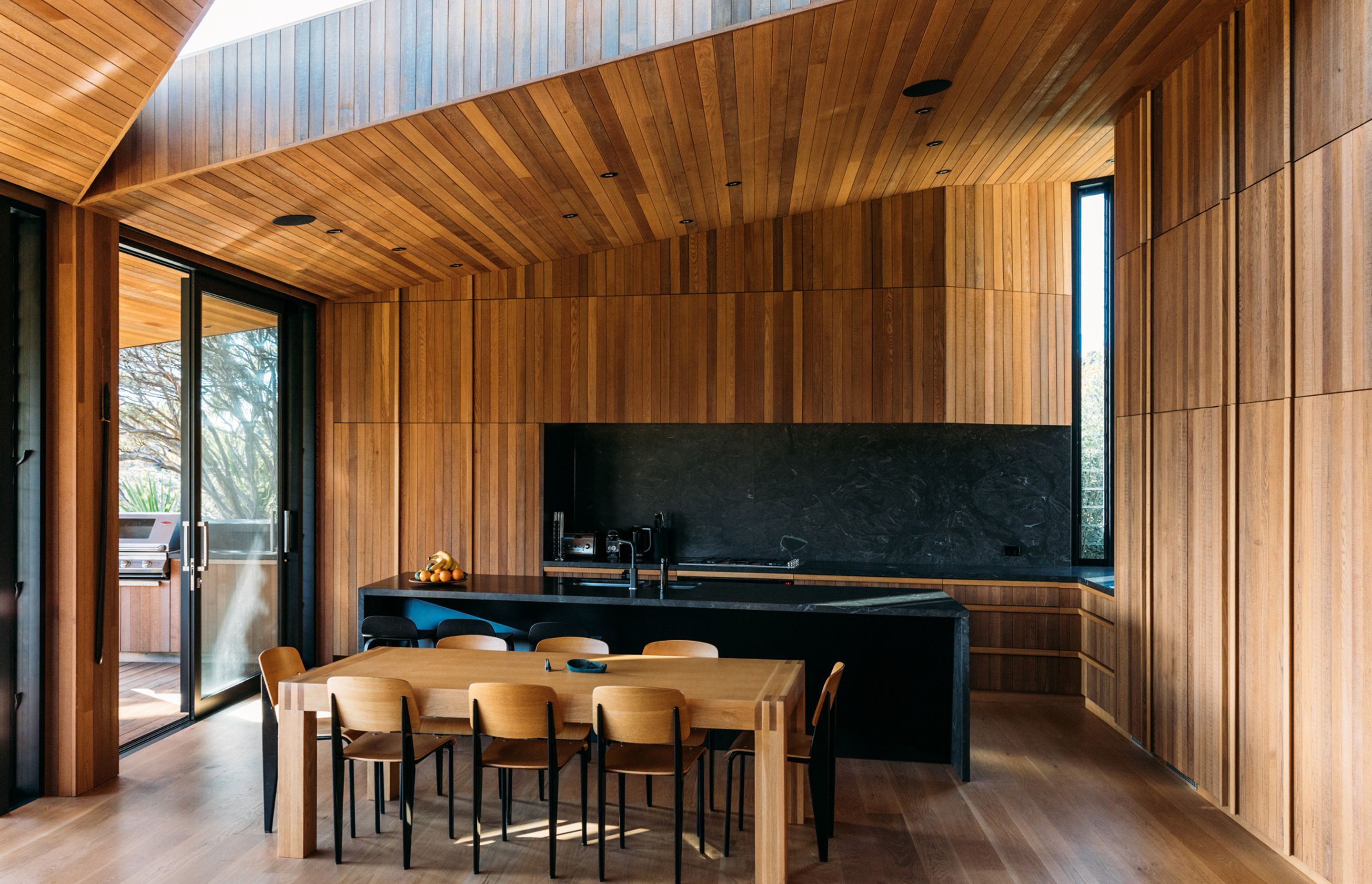 Integrated appliances and cabinetry, coupled with the black of the granite, helps the kitchen recede into the background of the open-plan living area.