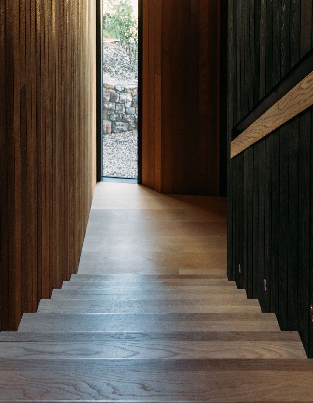 A full-height window on the south-western facade admits light into the stairwell, which features black and natural stained cedar.